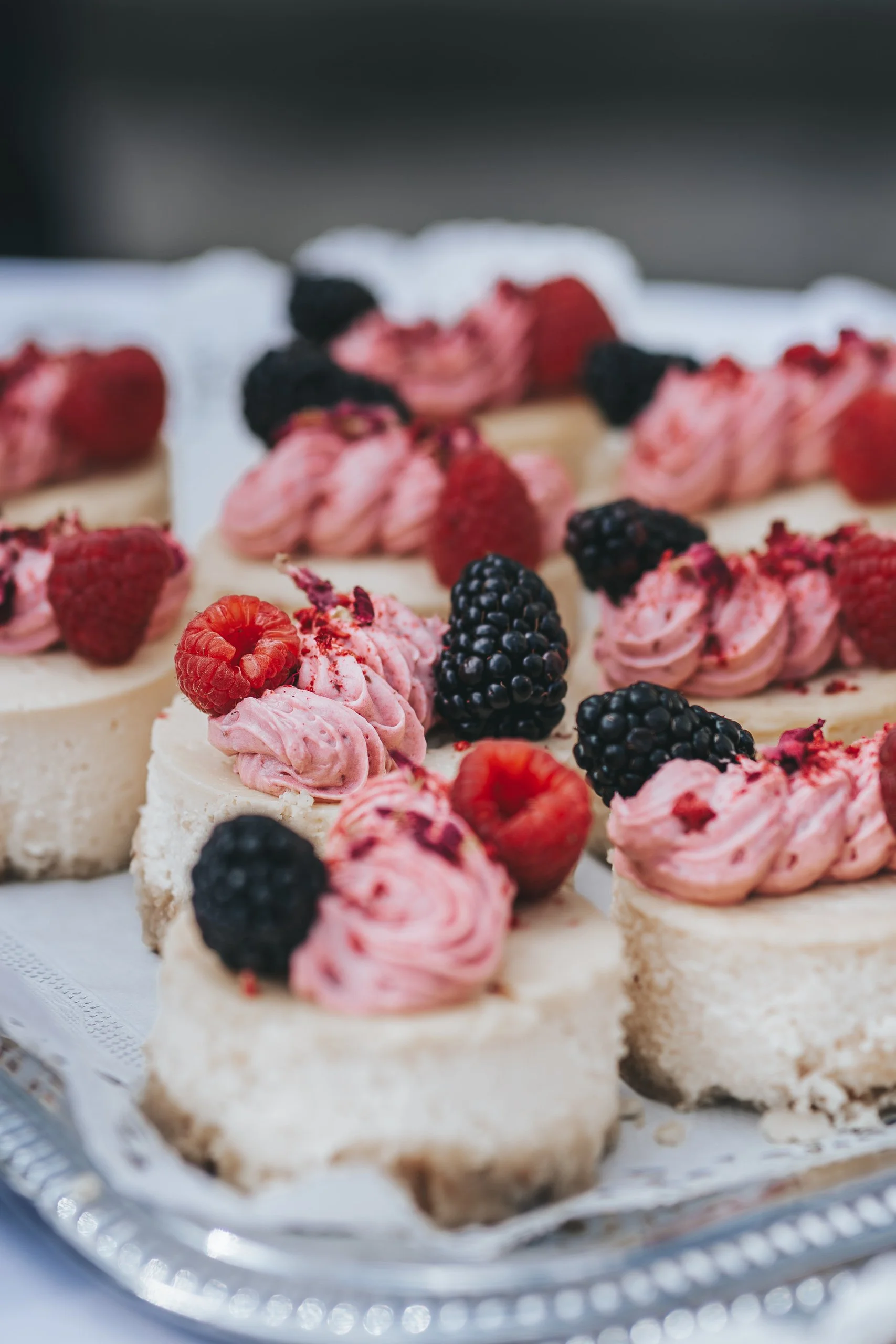 Kleine Kuchenstücke mit rosa Creme, Beeren und Himbeeren