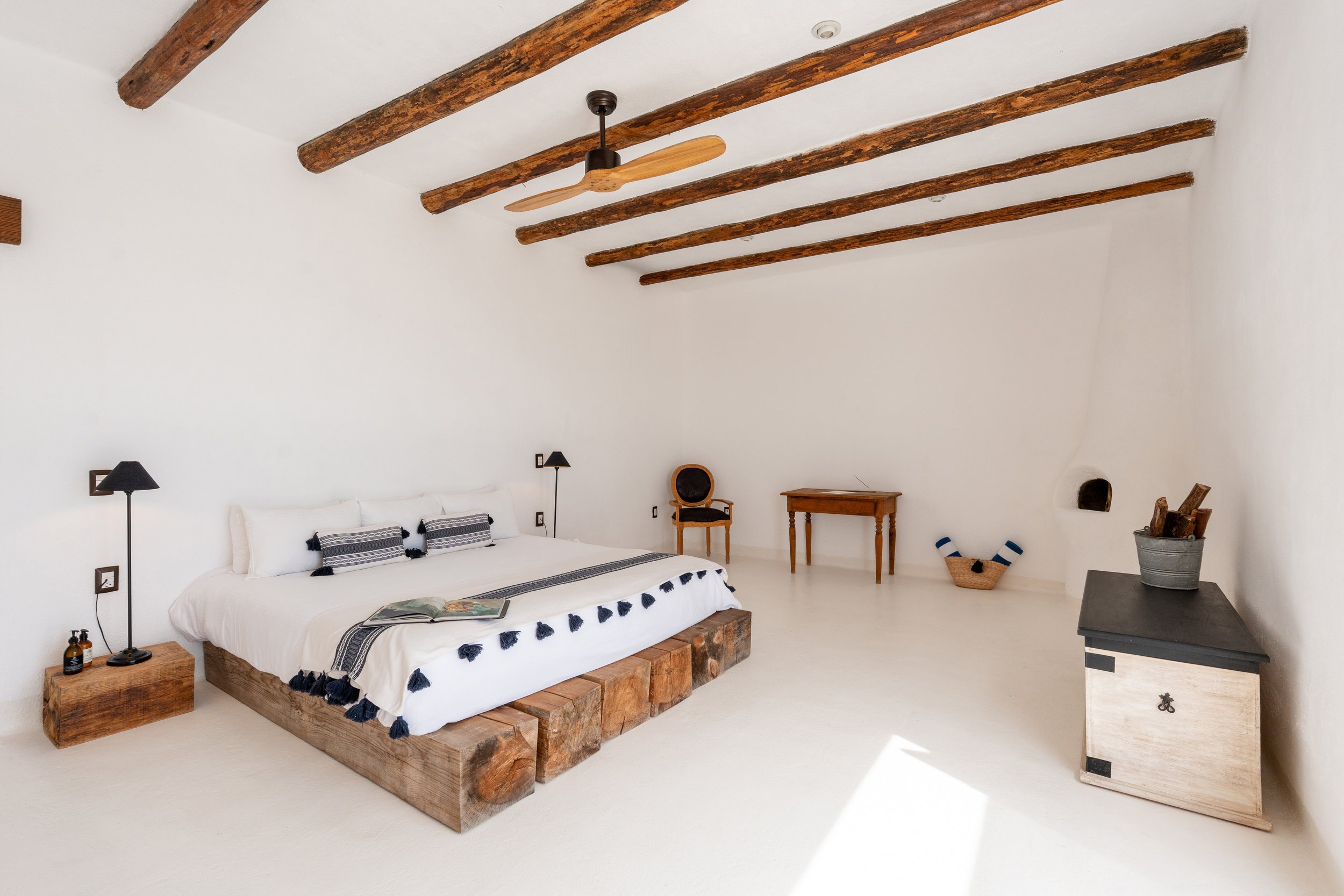 Spacious master bedroom of the East Cape Ocean View Two Bedroom Suite at NEST Baja, featuring rustic wooden beams, minimalist design, and high quality furniture.