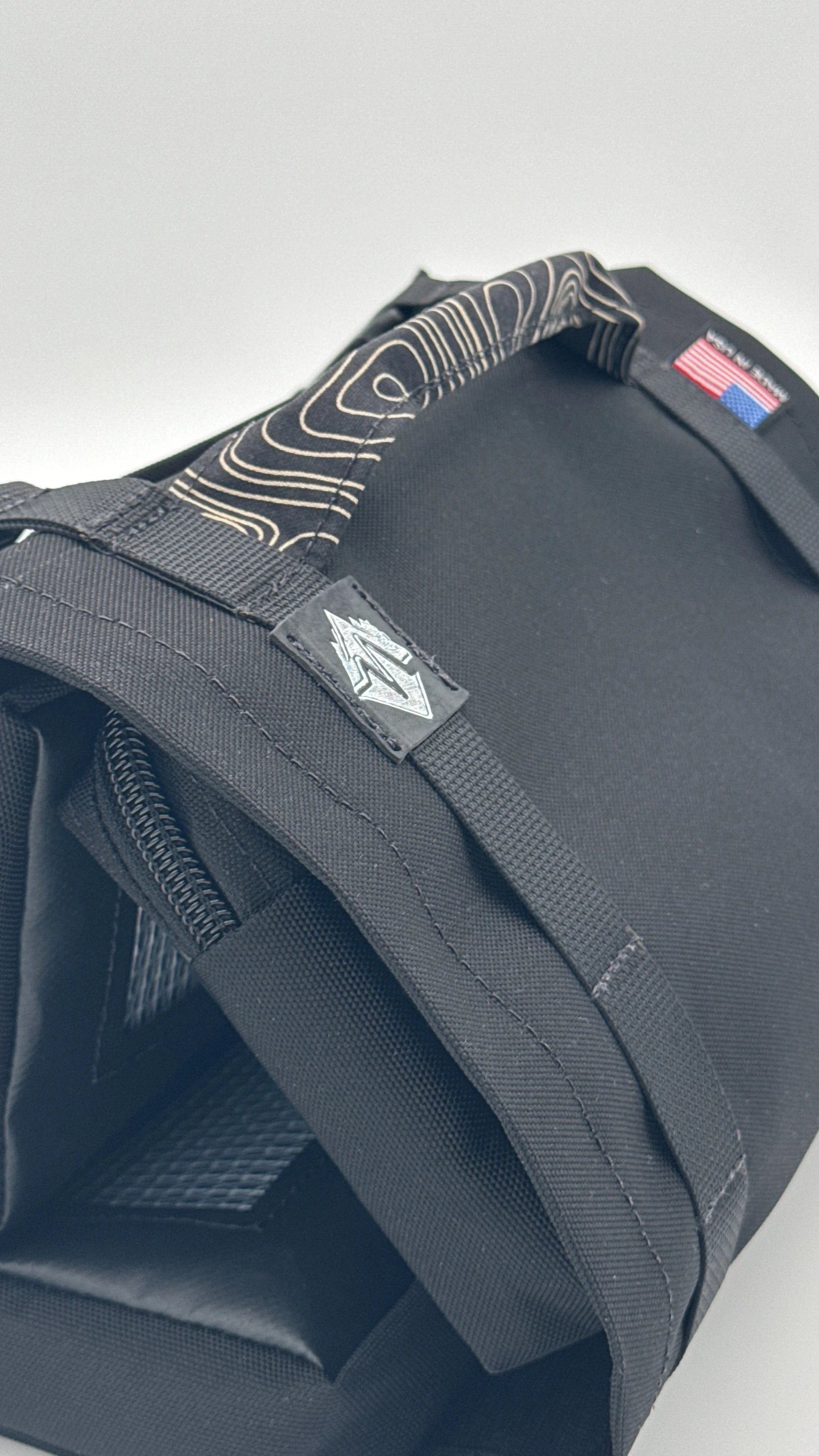 Close-up of a black tool roll, with an embossed logo and topographic pattern handle.