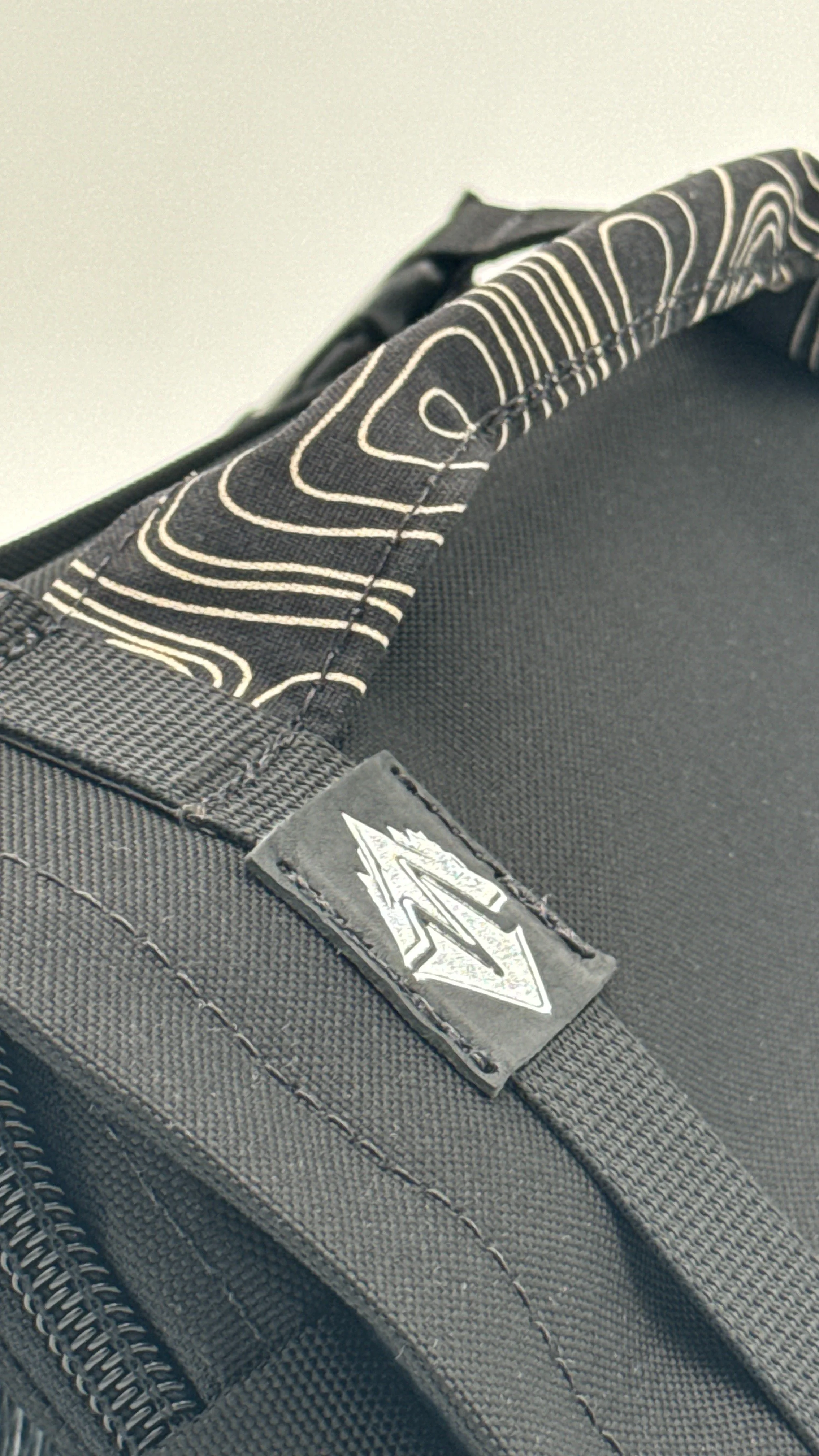 Close-up of a black tool roll, with an embossed logo and topographic pattern handle.
