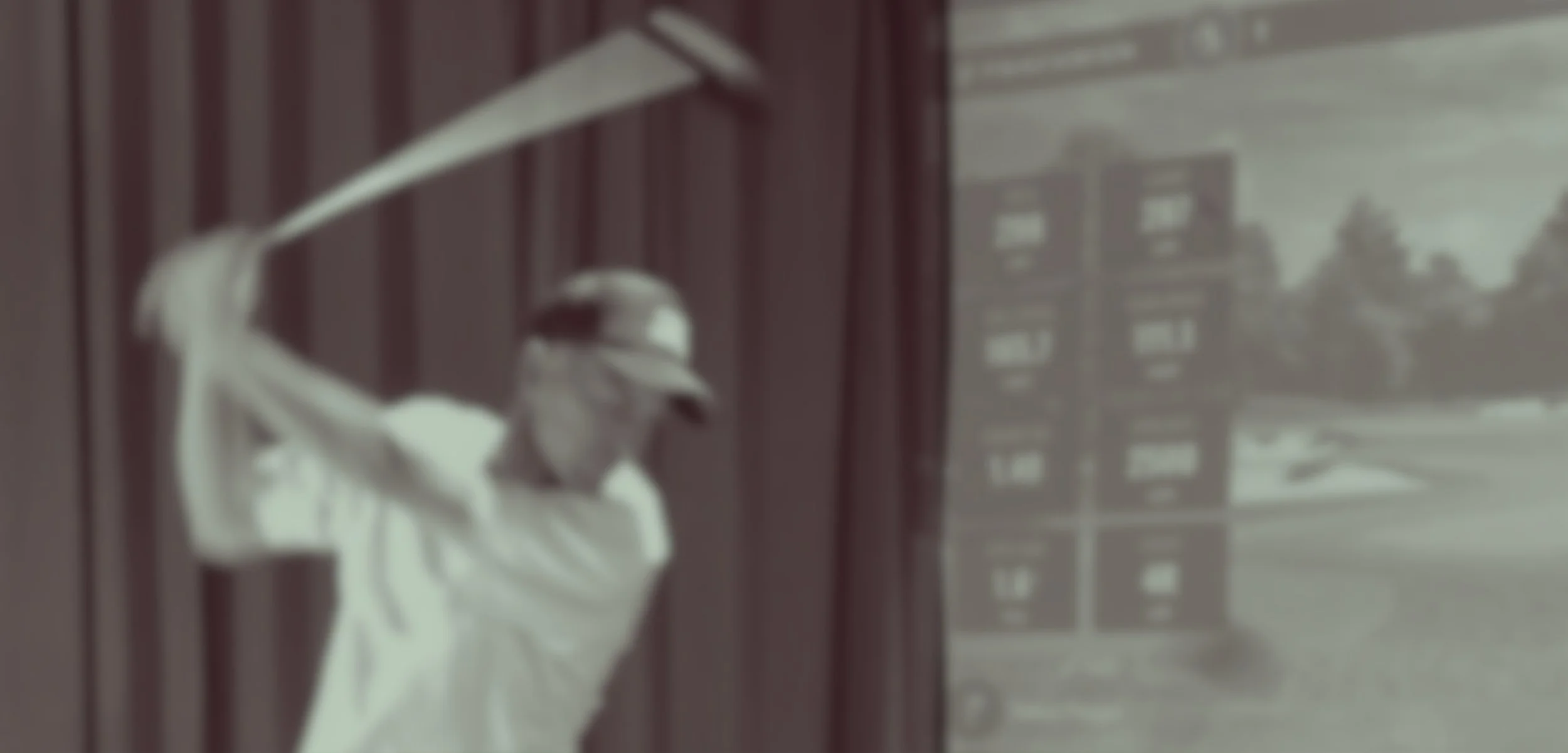 Unblurred image of a baseball player swinging a bat indoors with a view of a building through the window.
