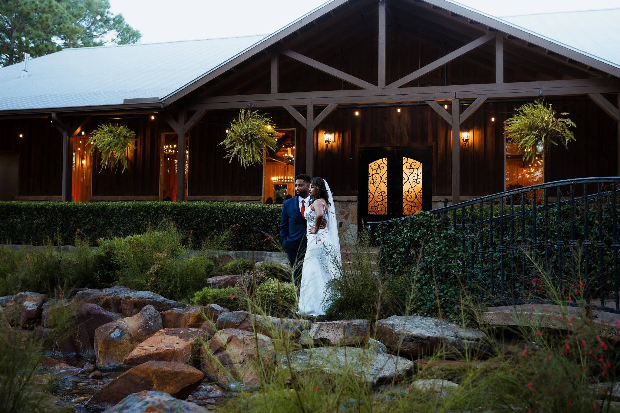 Bride and groom standing outside in front of a rustic barn during a wedding.