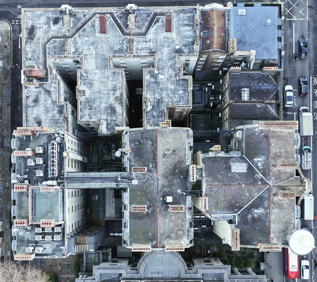 Aerial view of multiple building rooftops with HVAC units, chimneys, and various rooftop structures.