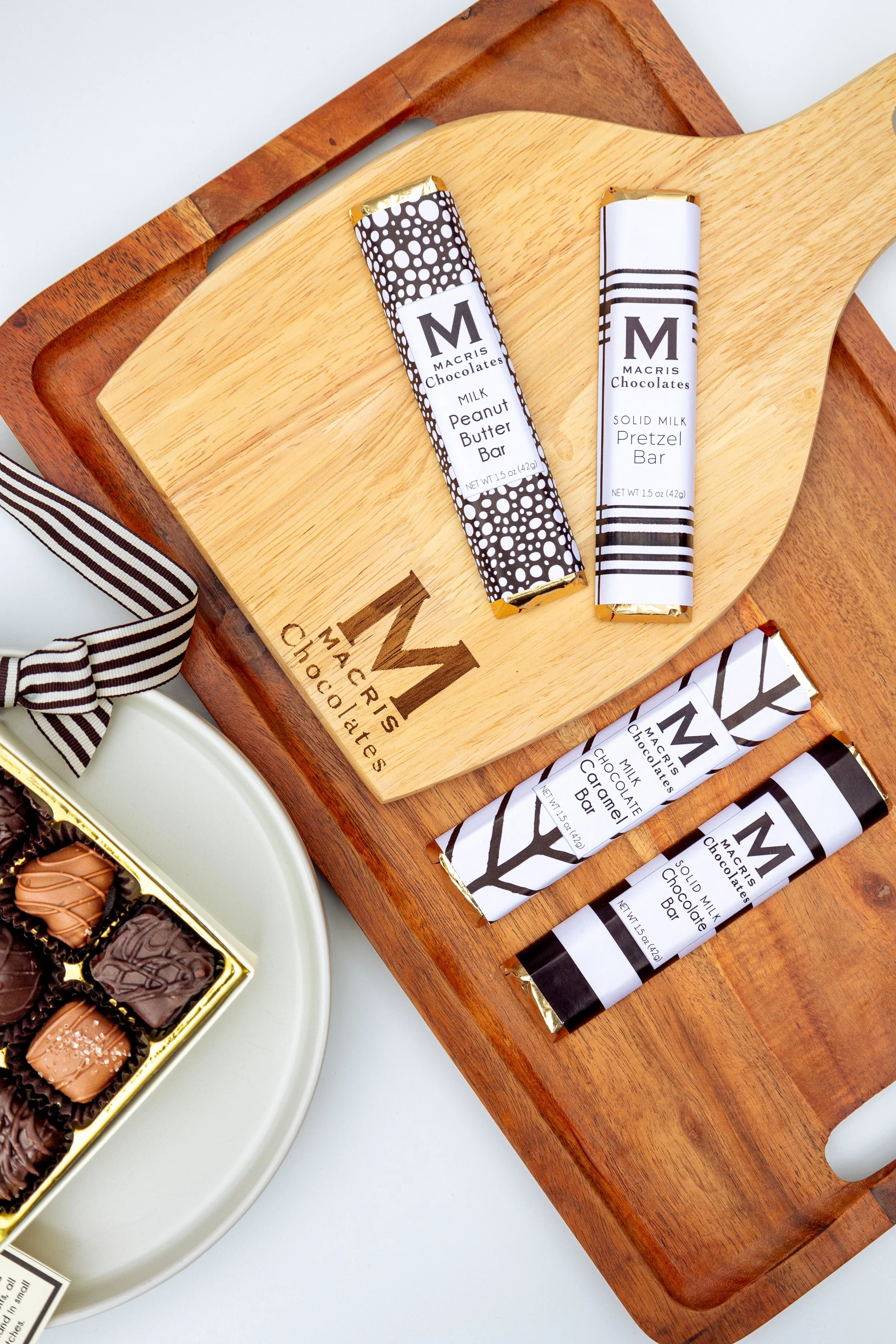 Product photography featuring assorted Macris Chocolates bars and boxed chocolates styled on neutral surfaces, highlighting packaging details, chocolate textures, and brand presentation in a clean, minimal, and classic setting.