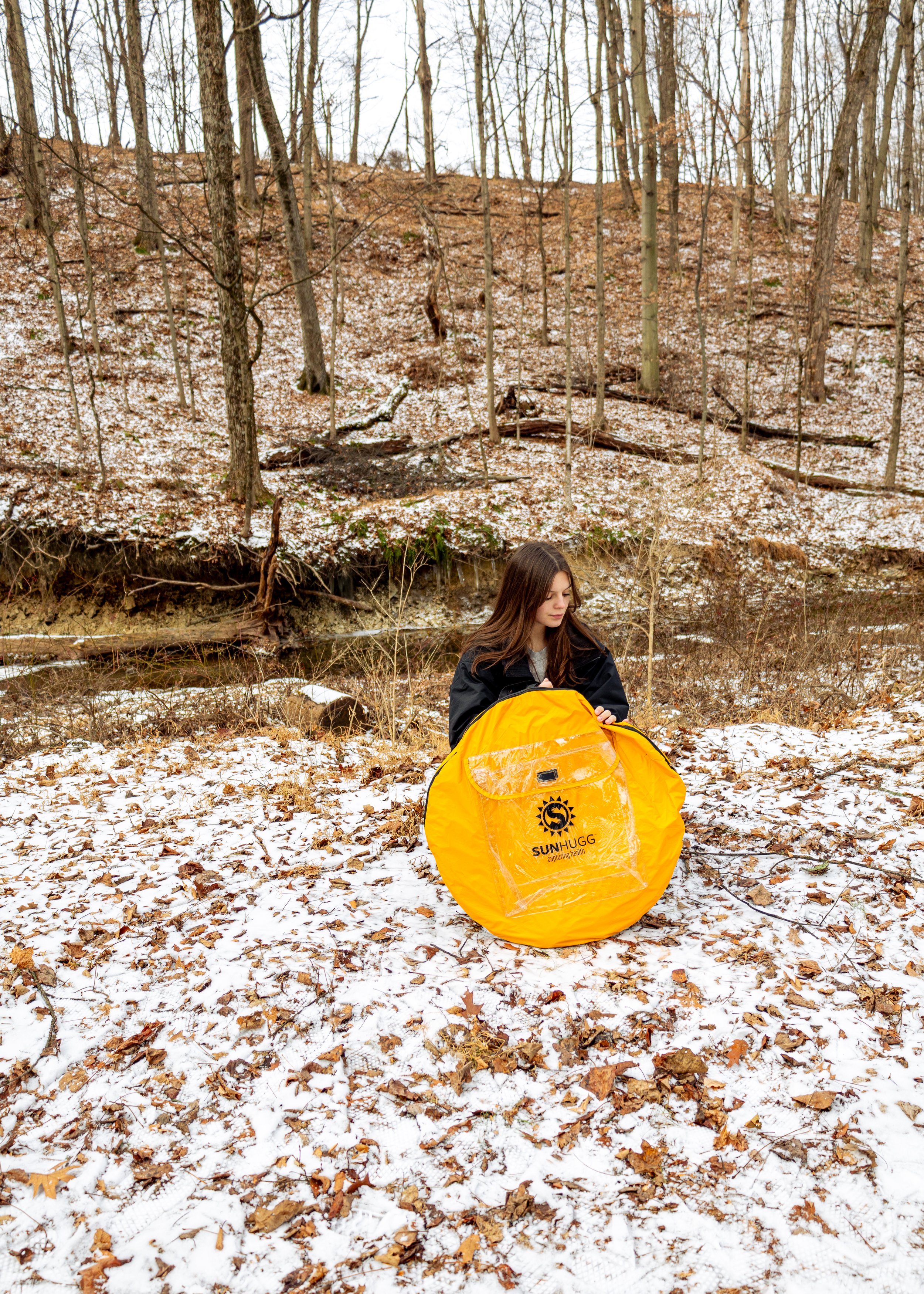 Lifestyle product photography featuring the SunHugg pop-up outdoor shelter, captured in a natural winter setting. Images highlight real-world use, setup and breakdown, interior details, branding elements, and scale to demonstrate functionality, porta