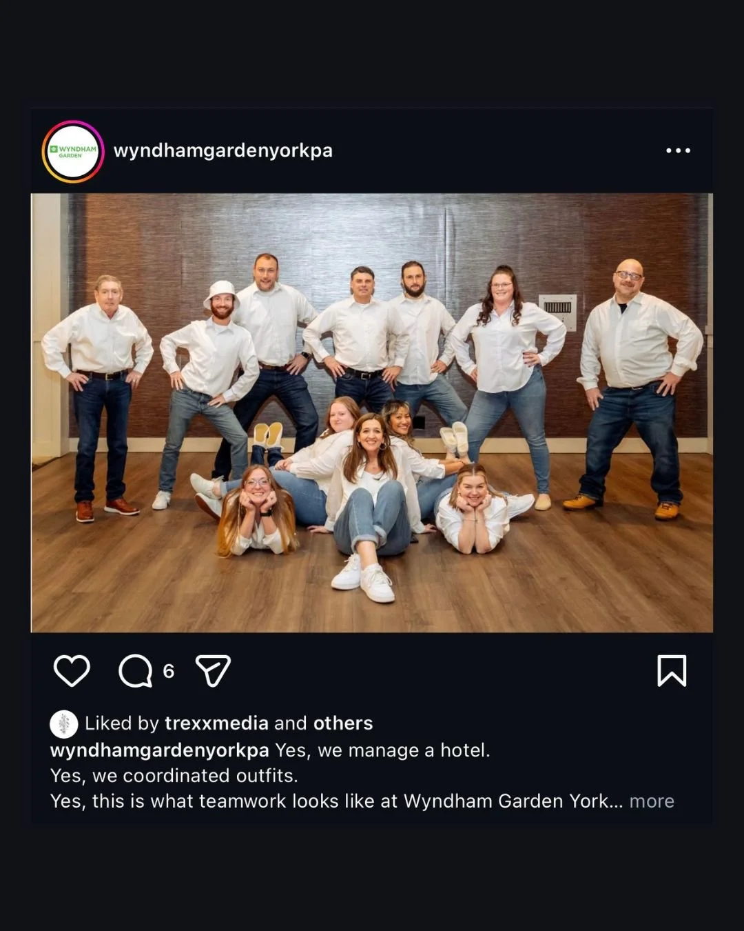 Group of hotel staff wearing coordinated white shirts and jeans posing playfully indoors at Wyndham Garden York.