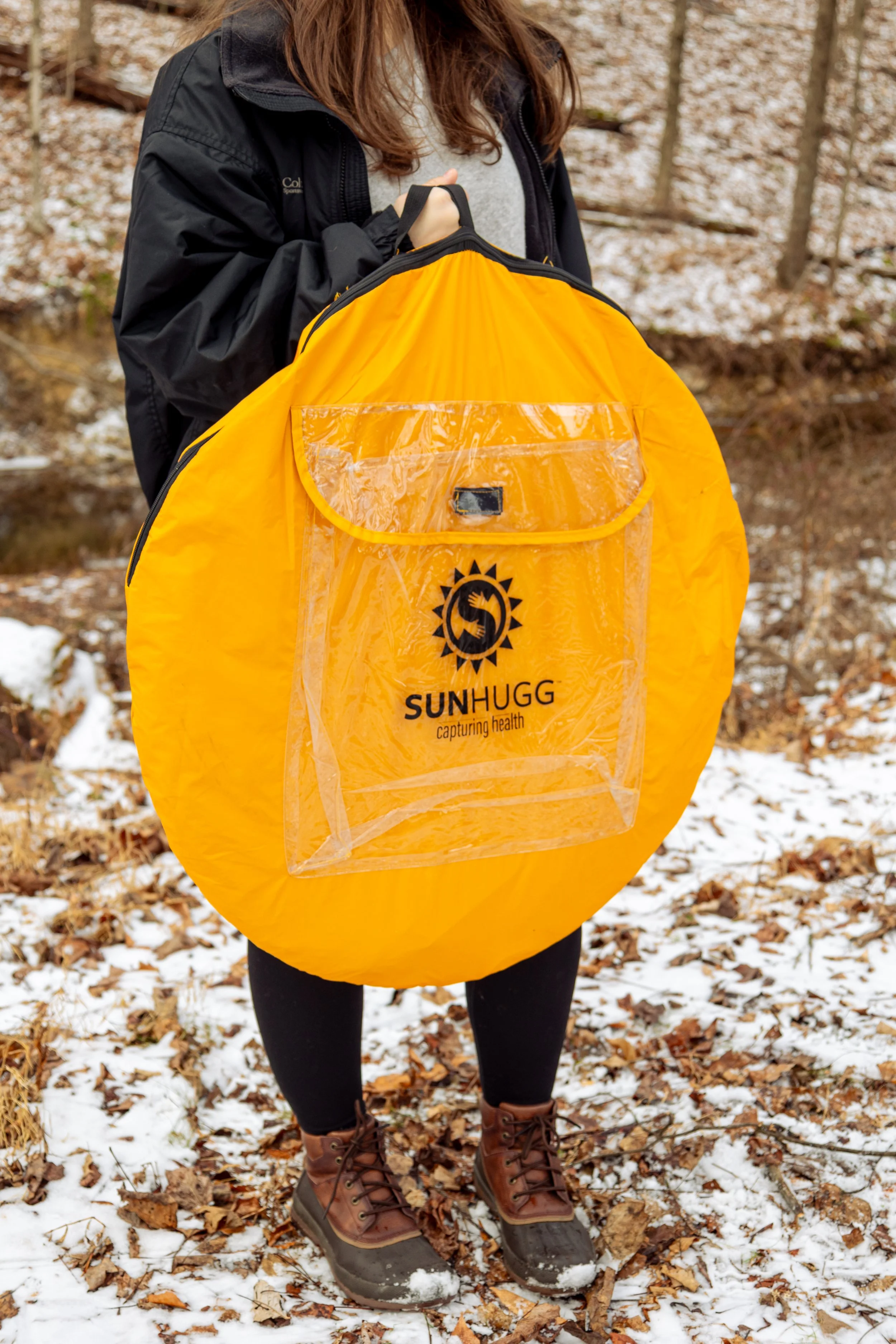 Lifestyle product photography featuring the SunHugg pop-up outdoor shelter, captured in a natural winter setting. Images highlight real-world use, setup and breakdown, interior details, branding elements, and scale to demonstrate functionality, porta