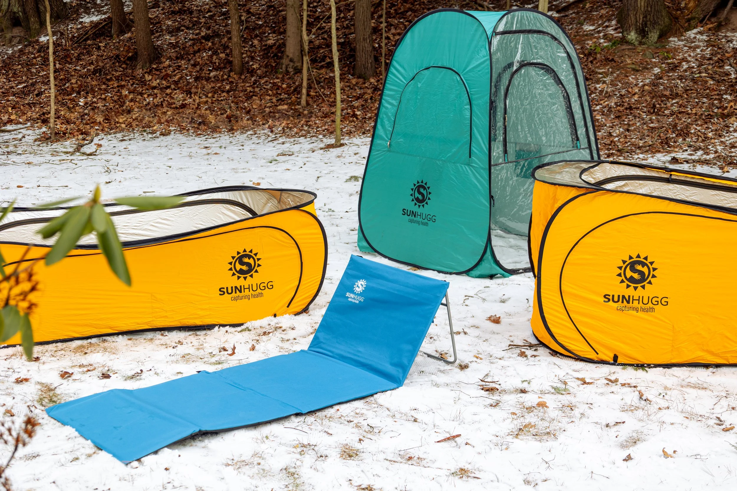 Lifestyle product photography featuring the SunHugg pop-up outdoor shelter, captured in a natural winter setting. Images highlight real-world use, setup and breakdown, interior details, branding elements, and scale to demonstrate functionality, porta