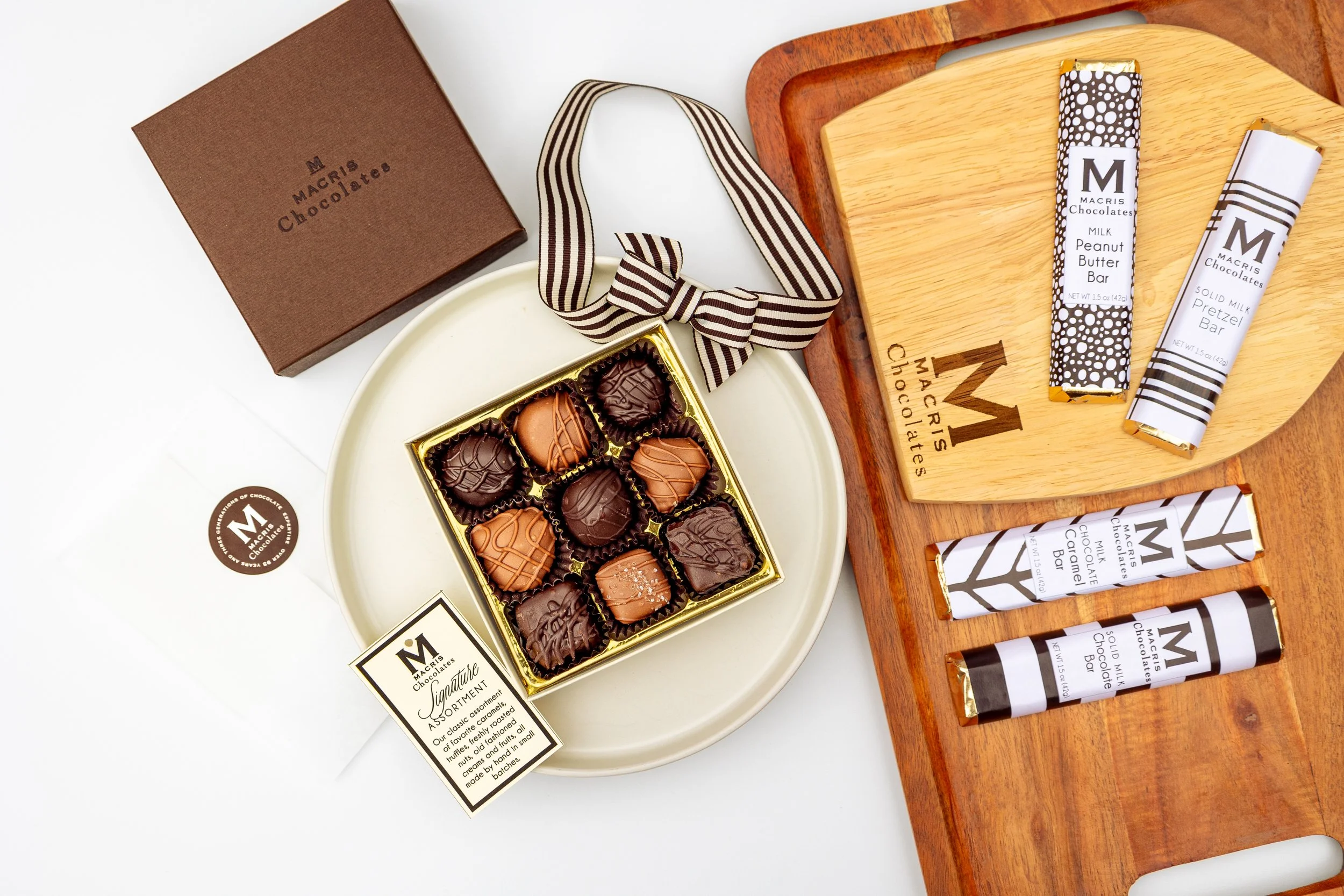 Product photography featuring assorted Macris Chocolates bars and boxed chocolates styled on neutral surfaces, highlighting packaging details, chocolate textures, and brand presentation in a clean, minimal, and classic setting.