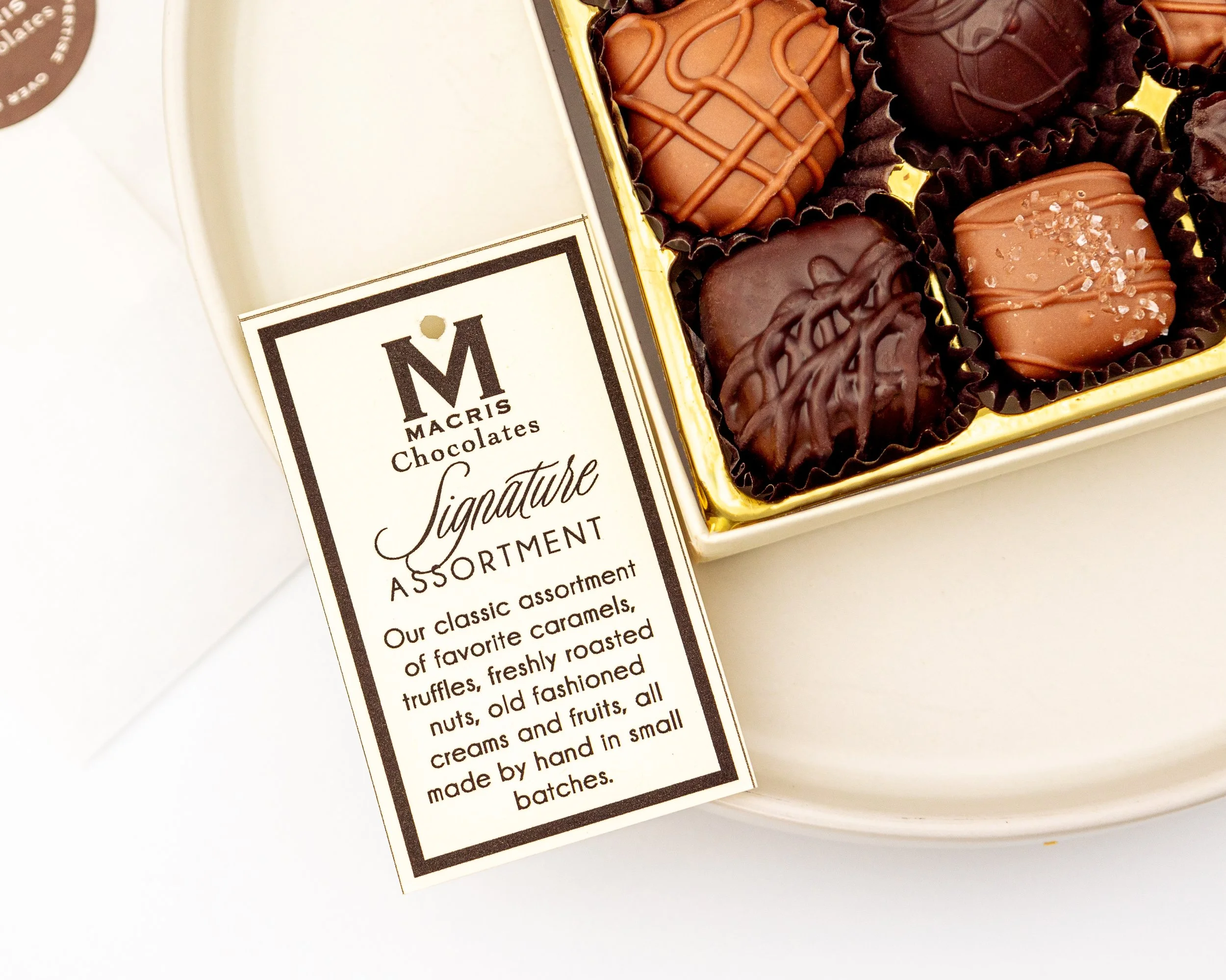 Product photography featuring assorted Macris Chocolates bars and boxed chocolates styled on neutral surfaces, highlighting packaging details, chocolate textures, and brand presentation in a clean, minimal, and classic setting.