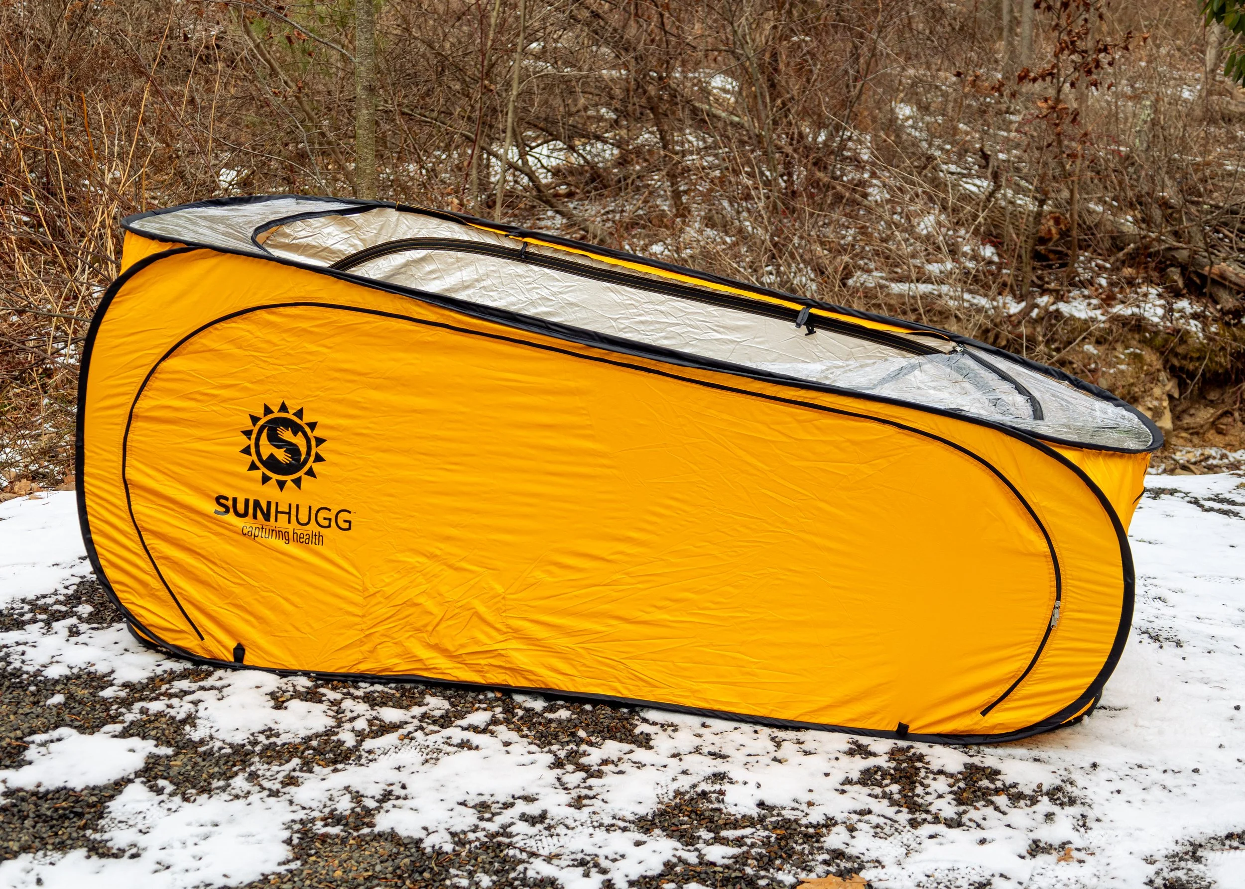 Lifestyle product photography featuring the SunHugg pop-up outdoor shelter, captured in a natural winter setting. Images highlight real-world use, setup and breakdown, interior details, branding elements, and scale to demonstrate functionality, porta
