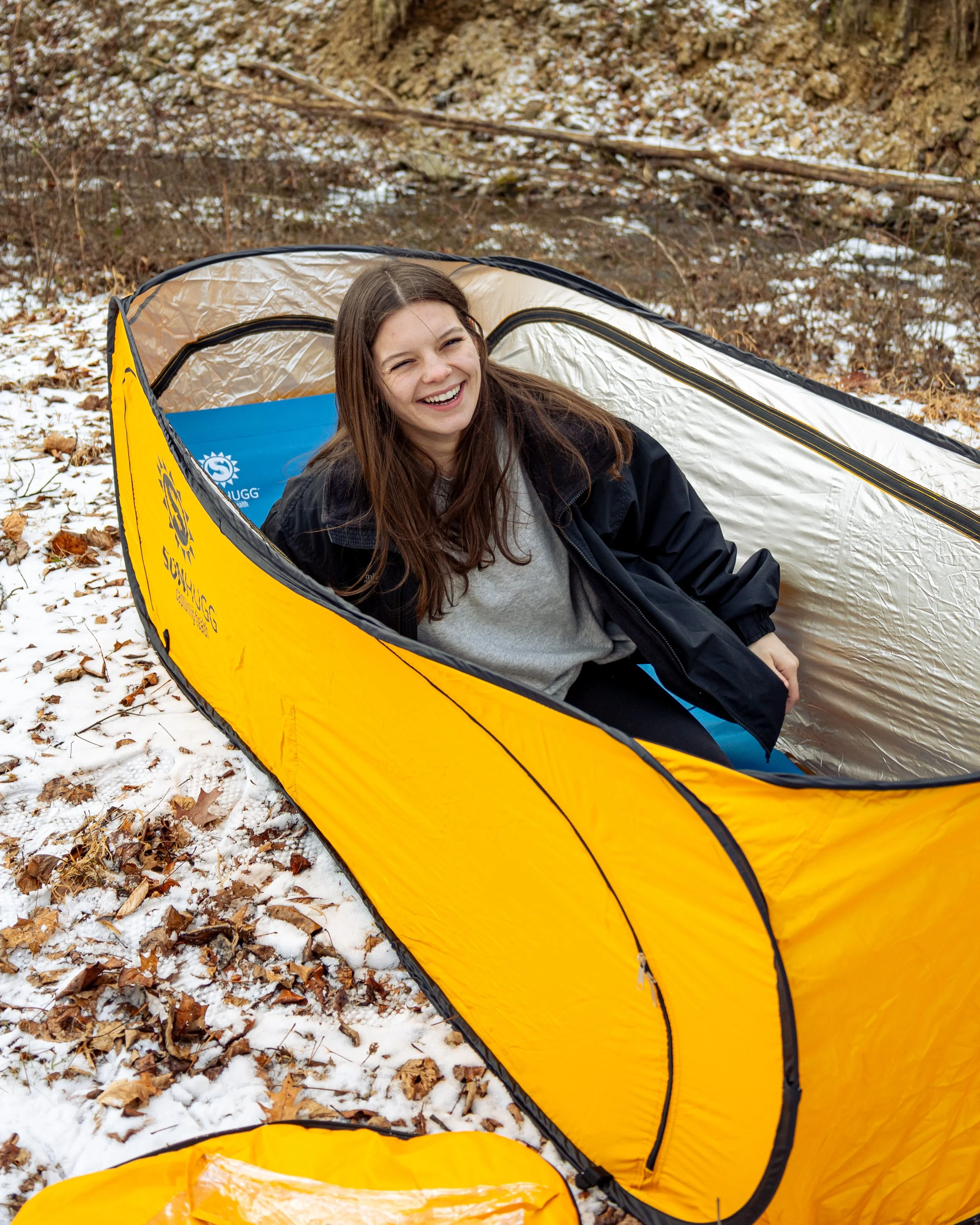 Lifestyle product photography featuring the SunHugg pop-up outdoor shelter, captured in a natural winter setting. Images highlight real-world use, setup and breakdown, interior details, branding elements, and scale to demonstrate functionality, porta