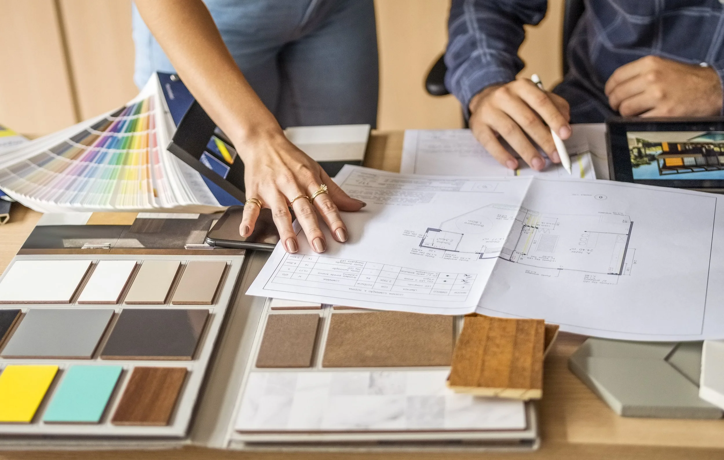 Two people reviewing design plans and color samples on a worktable.