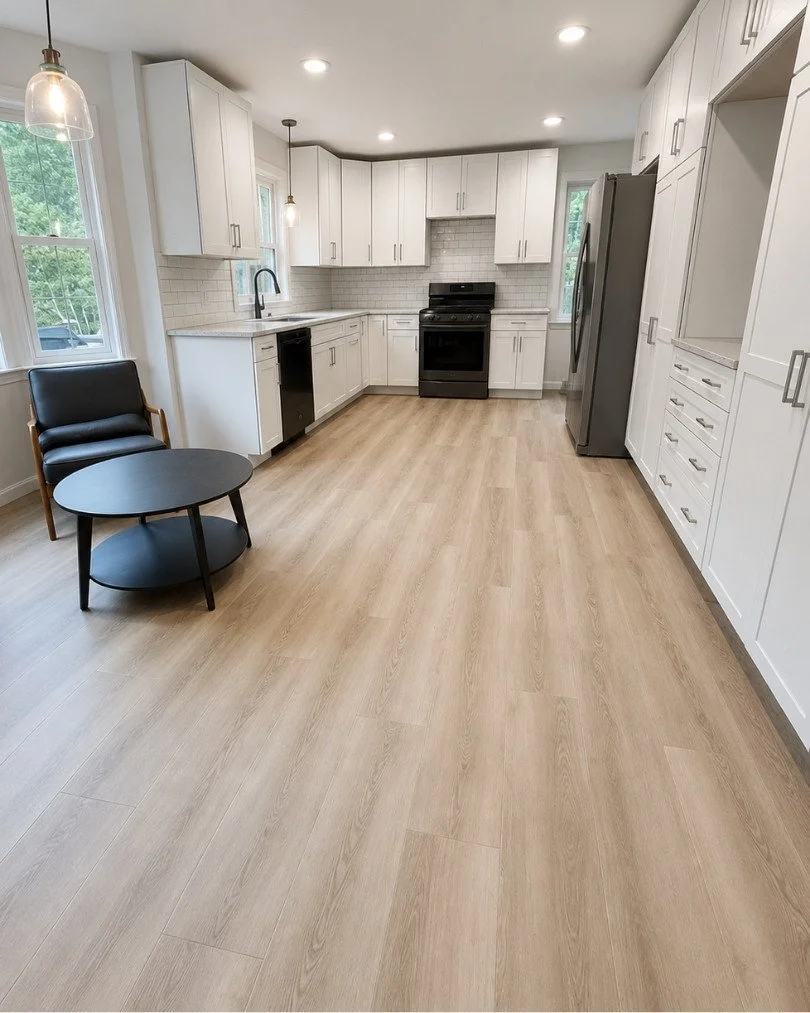 Modern kitchen with light wood-look luxury vinyl plank flooring, white shaker cabinets, subway tile backsplash, and stainless steel appliances installed by JK Flooring & Tile.
