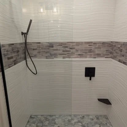 Custom walk-in shower with white subway tile walls, decorative accent tile band, and black plumbing fixtures installed by JK Flooring & Tile.