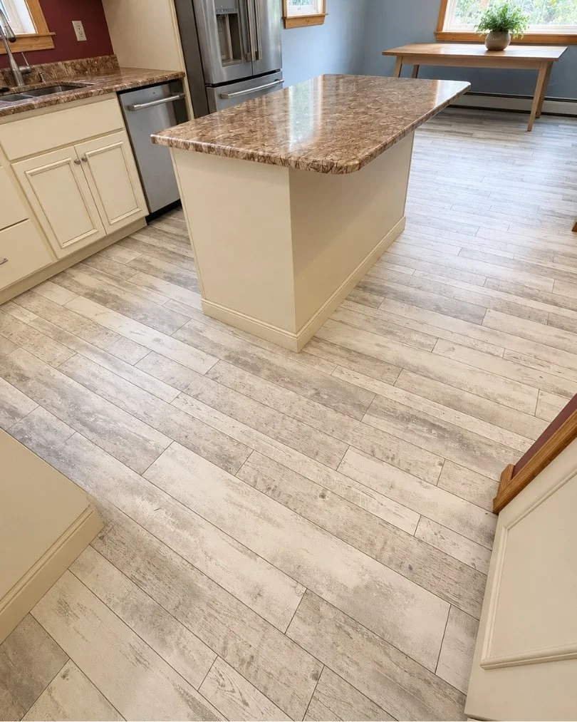 Luxury vinyl plank flooring installation in a modern kitchen featuring white cabinets, stainless steel appliances, and durable wood-look LVP flooring.