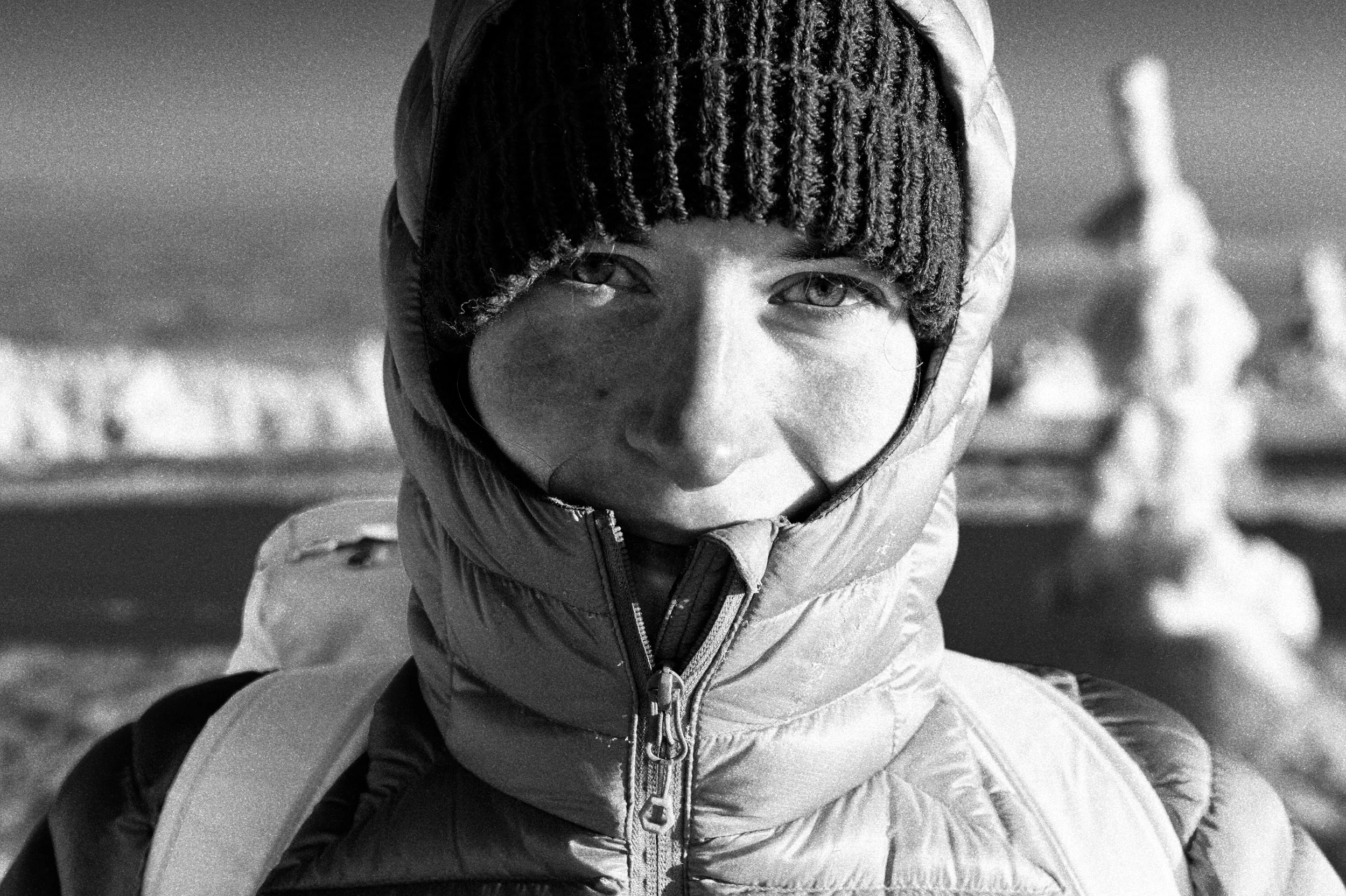 Black and white portrait of a hiker in cold weather gear, with snow covered trees behind. Finnish lappland