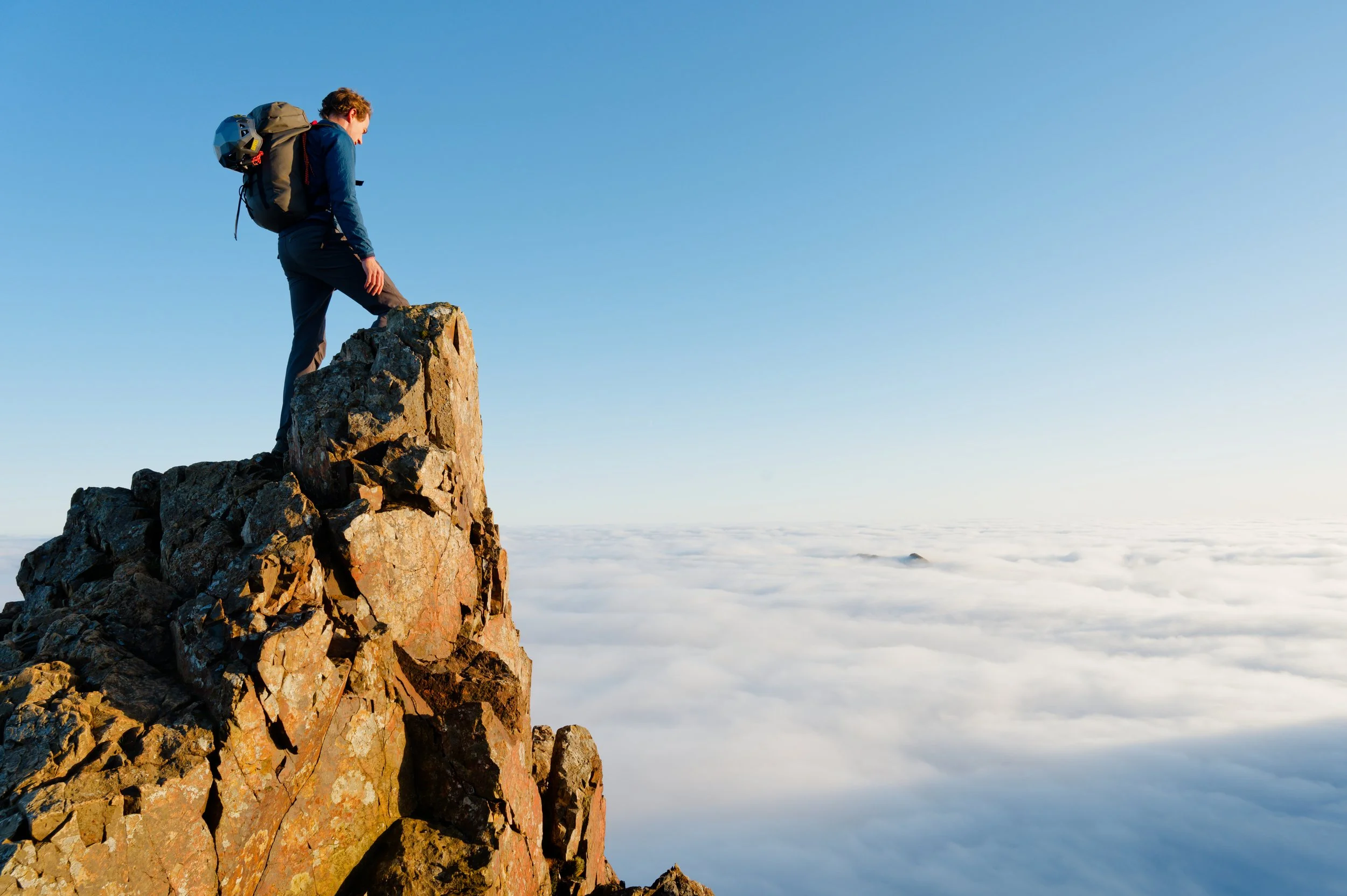Crib Goch, Eryri National Park, Wales. A mountaineer standing on Crib Goch ridge overlooking a cloud inversion.