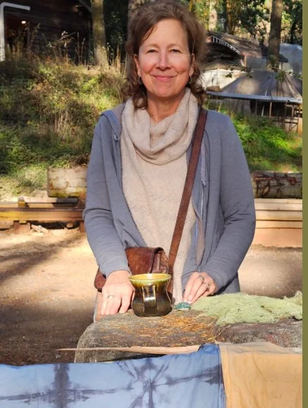 Woman standing outdoors with pottery and fabric on table