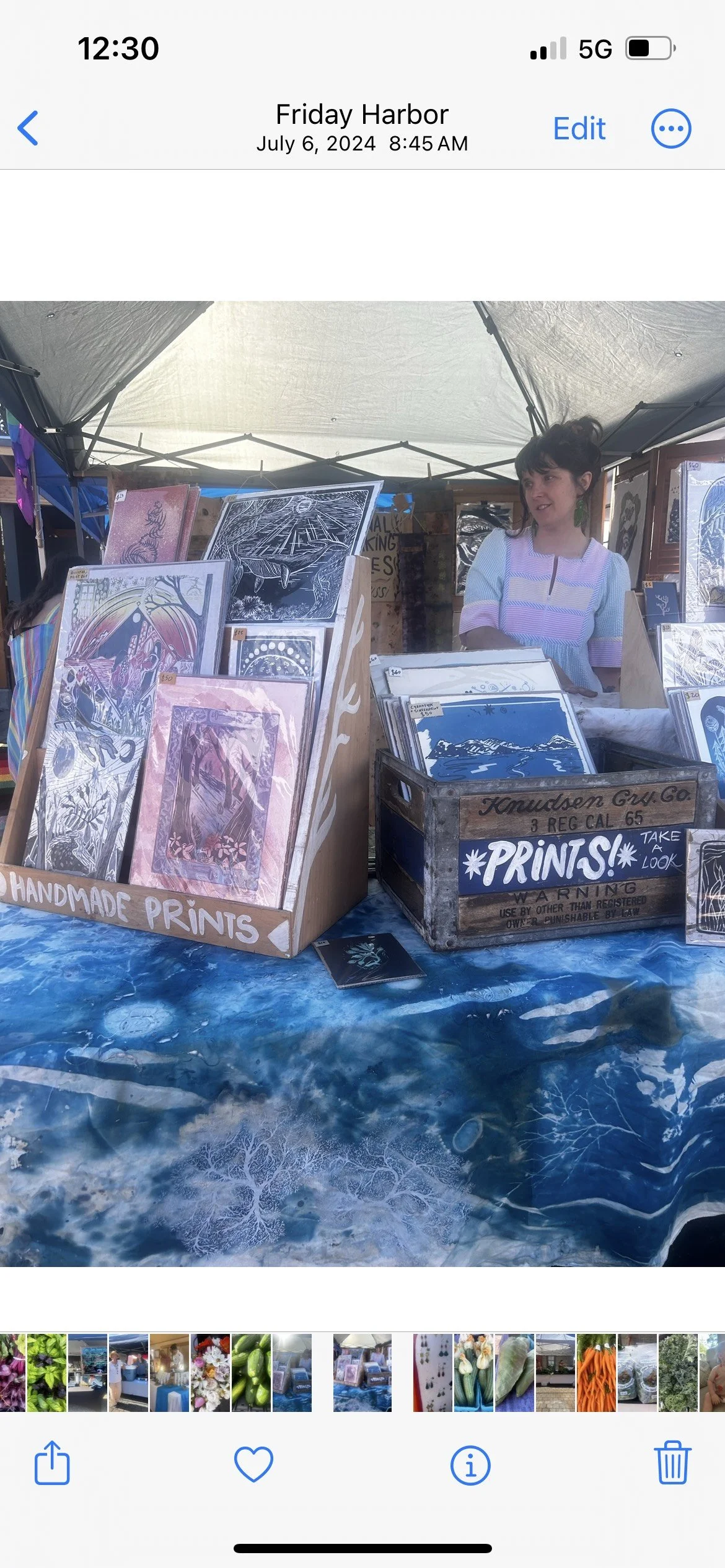 Art booth with handmade prints on display, woman behind table, Friday Harbor fair.