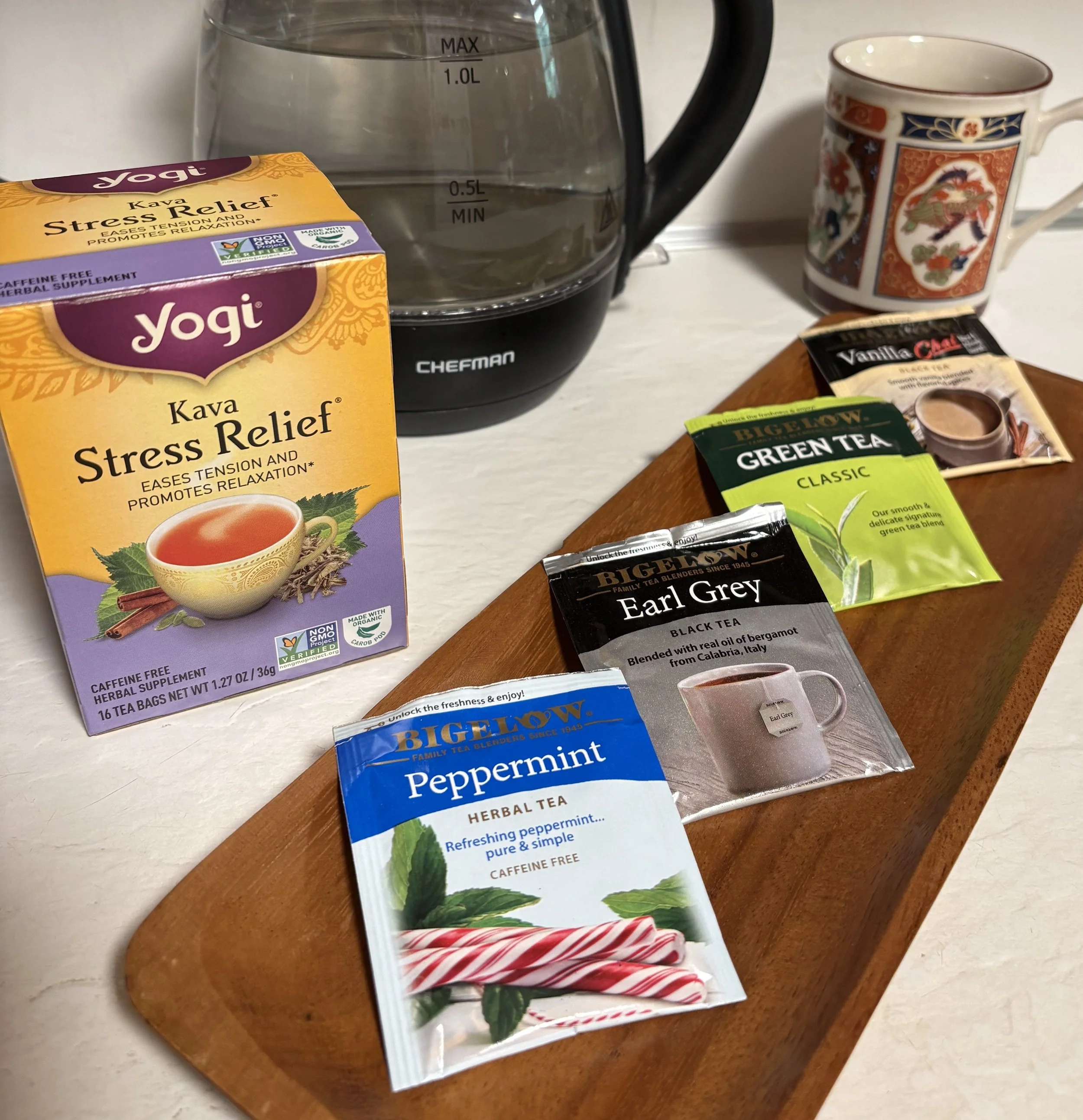 Assortment of hot tea options in front  of a tea kettle and cup