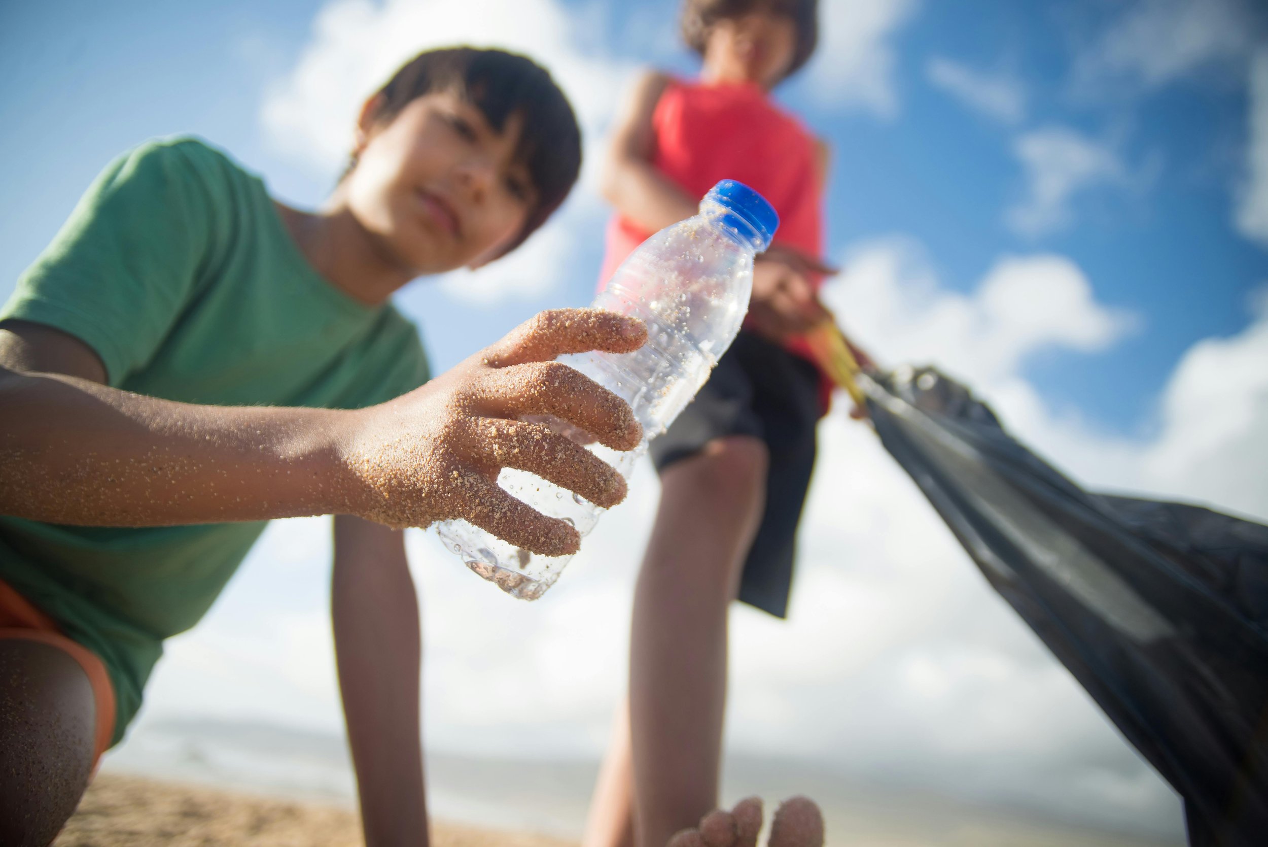 A child picks up litter on the beach