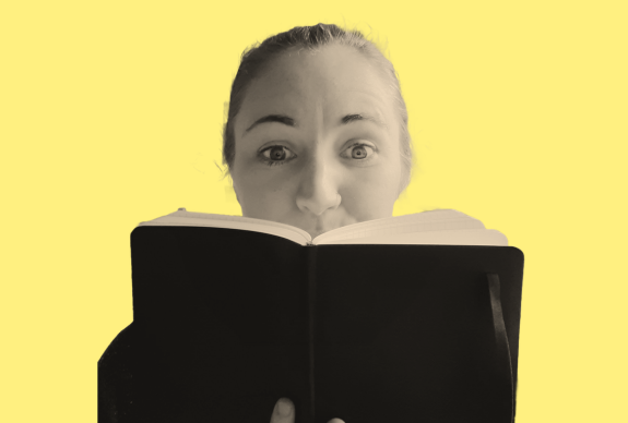 Female copywriter and brand messaging consultant peering inside a black notebook