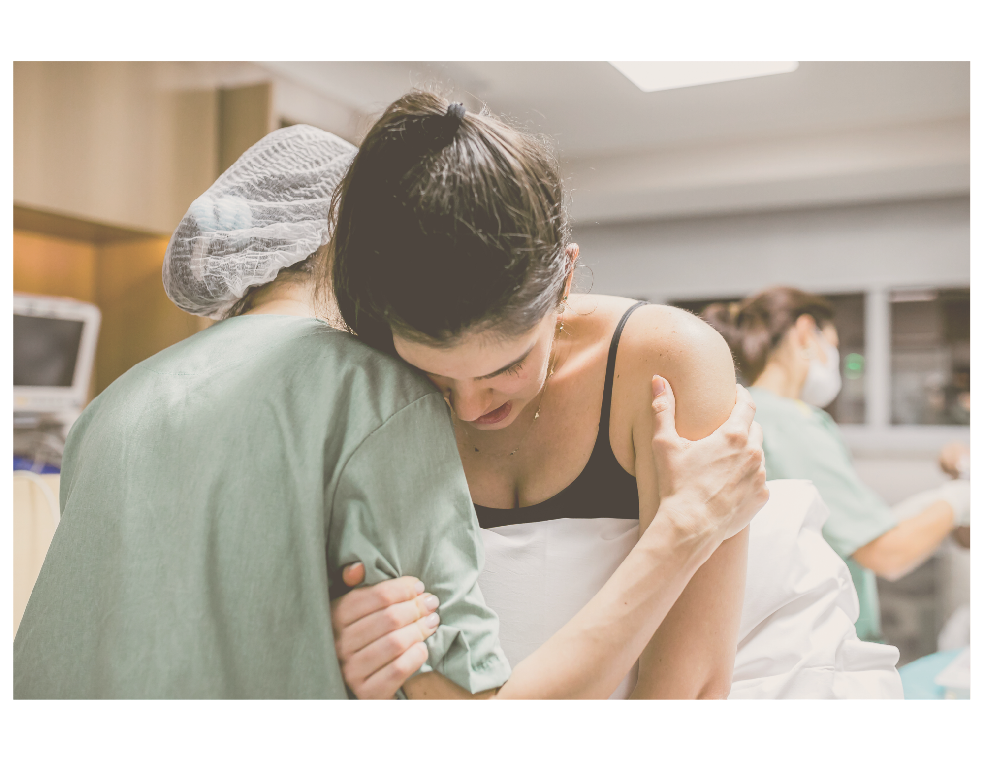 A woman in a hospital bed being comforted by a doula during childbirth.