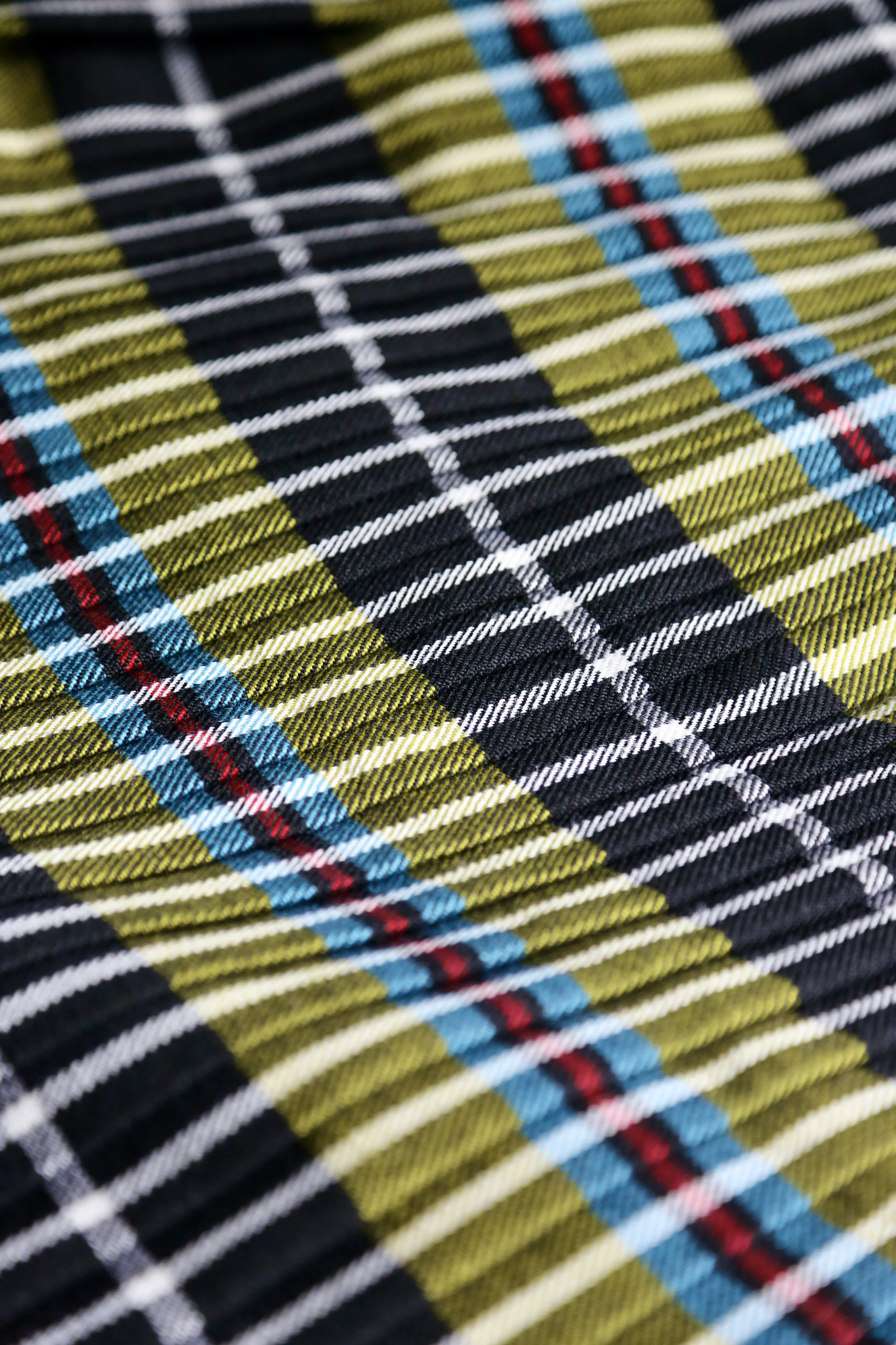 Close-up of a colorful tartan plaid fabric with yellow, black, white, red, and blue stripes.