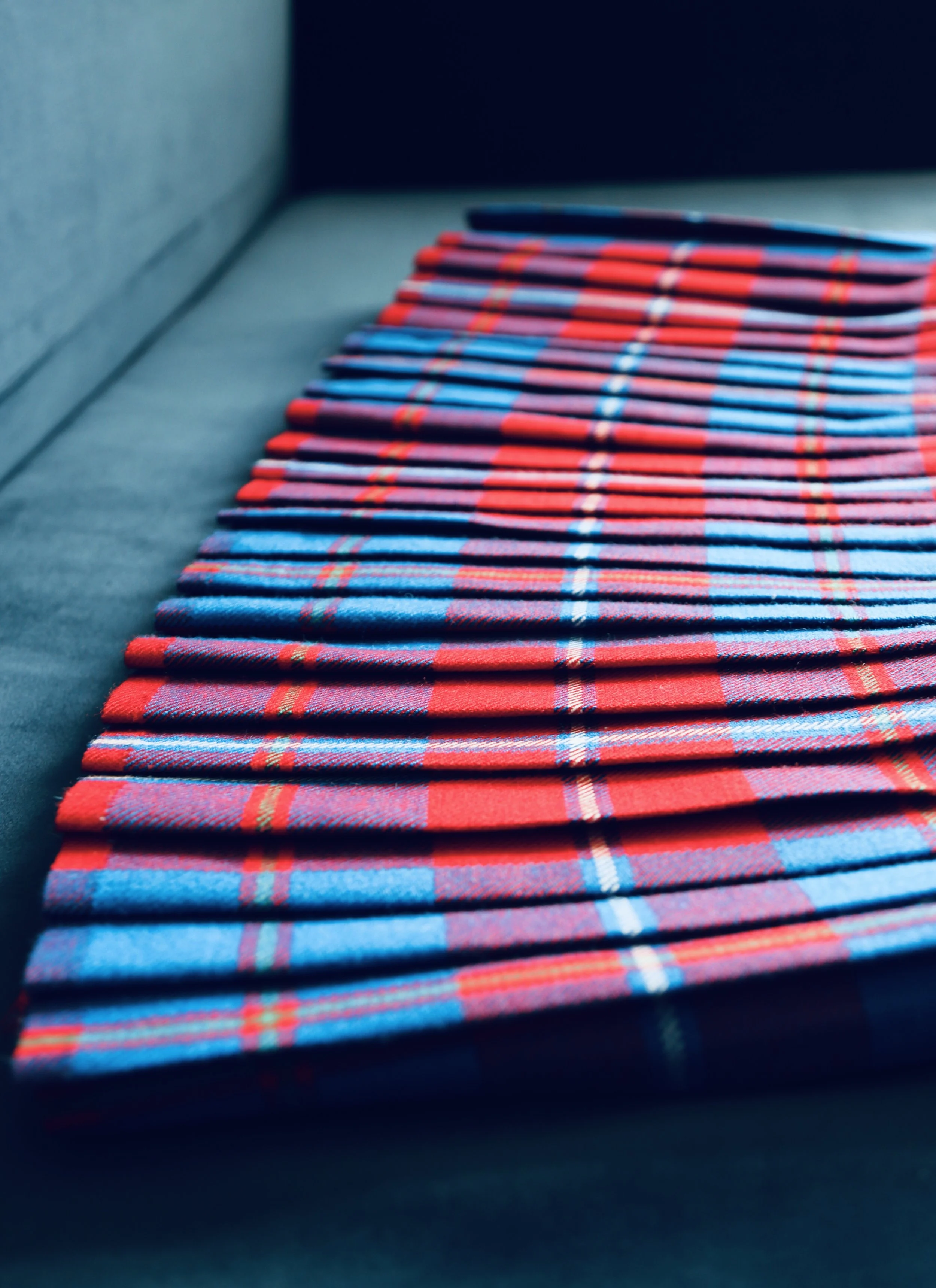 Stacked folded red and blue plaid fabric kilt on a table.