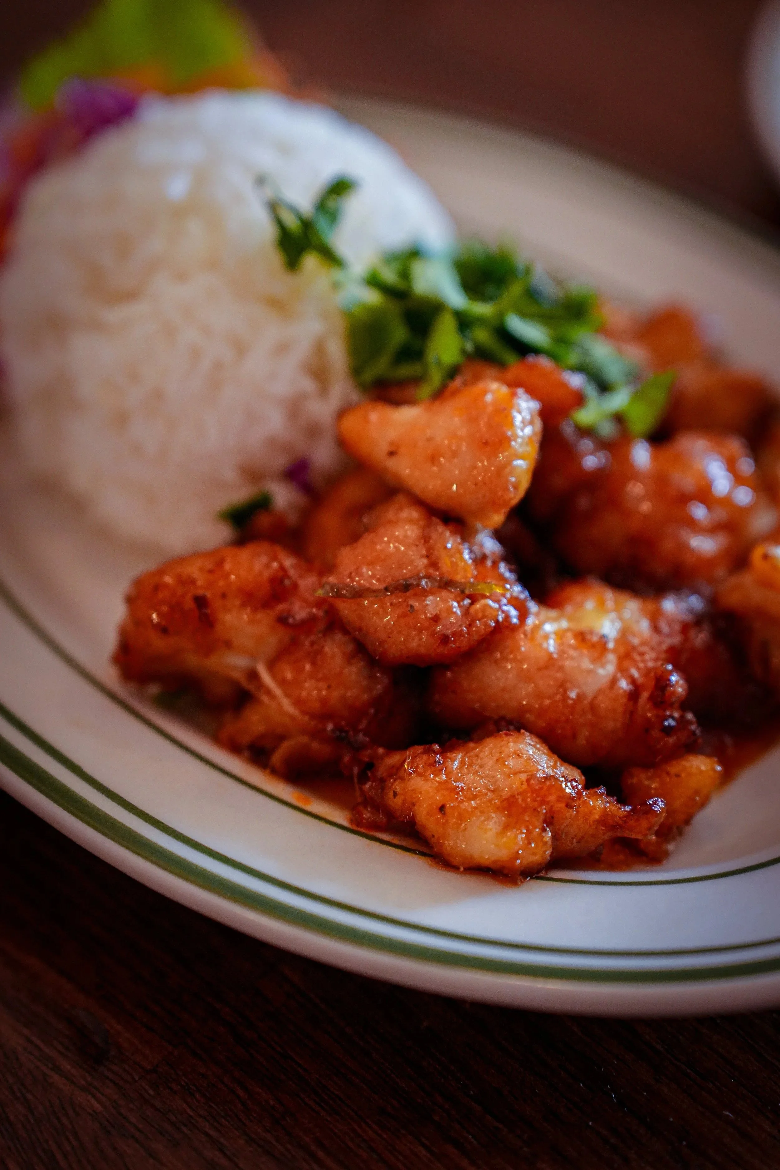 A plate with white rice, garnished with herbs, and crispy fried chicken chunks on the side.
