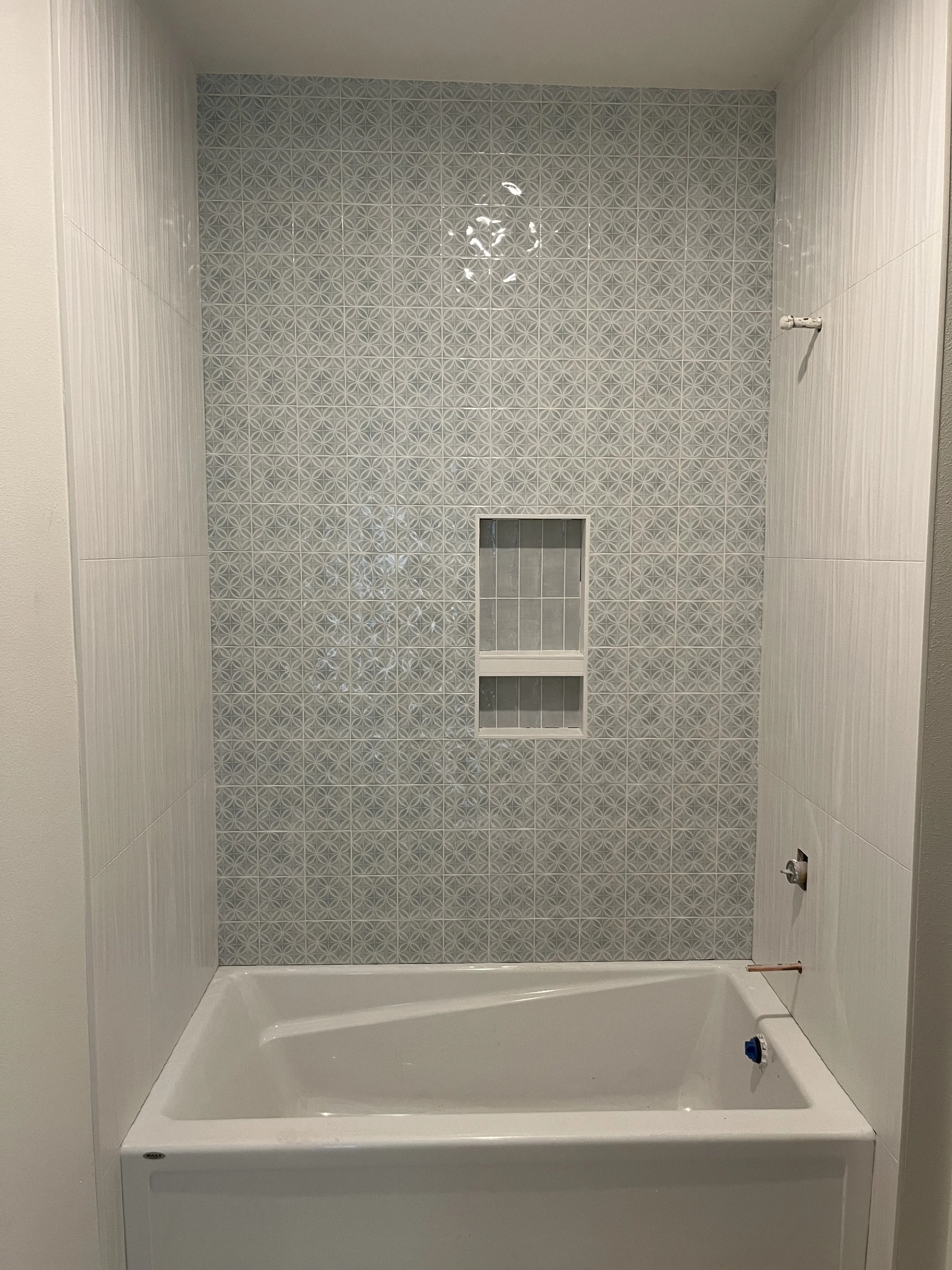 Empty bathtub in a bathroom with patterned tiles on the wall