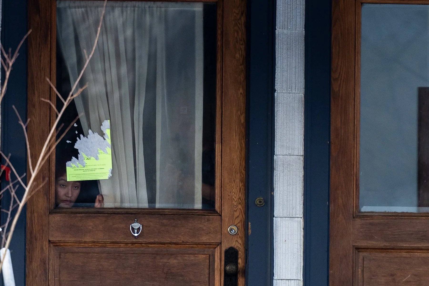 A person looks out their window at the scene unfolding on Portland Avenue in Minneapolis, Minn., after 37-year-old Renee Good was fatally shot by U.S. Immigration and Customs Enforcement agent Jonathan Ross on Wednesday, Jan. 7, 2026.