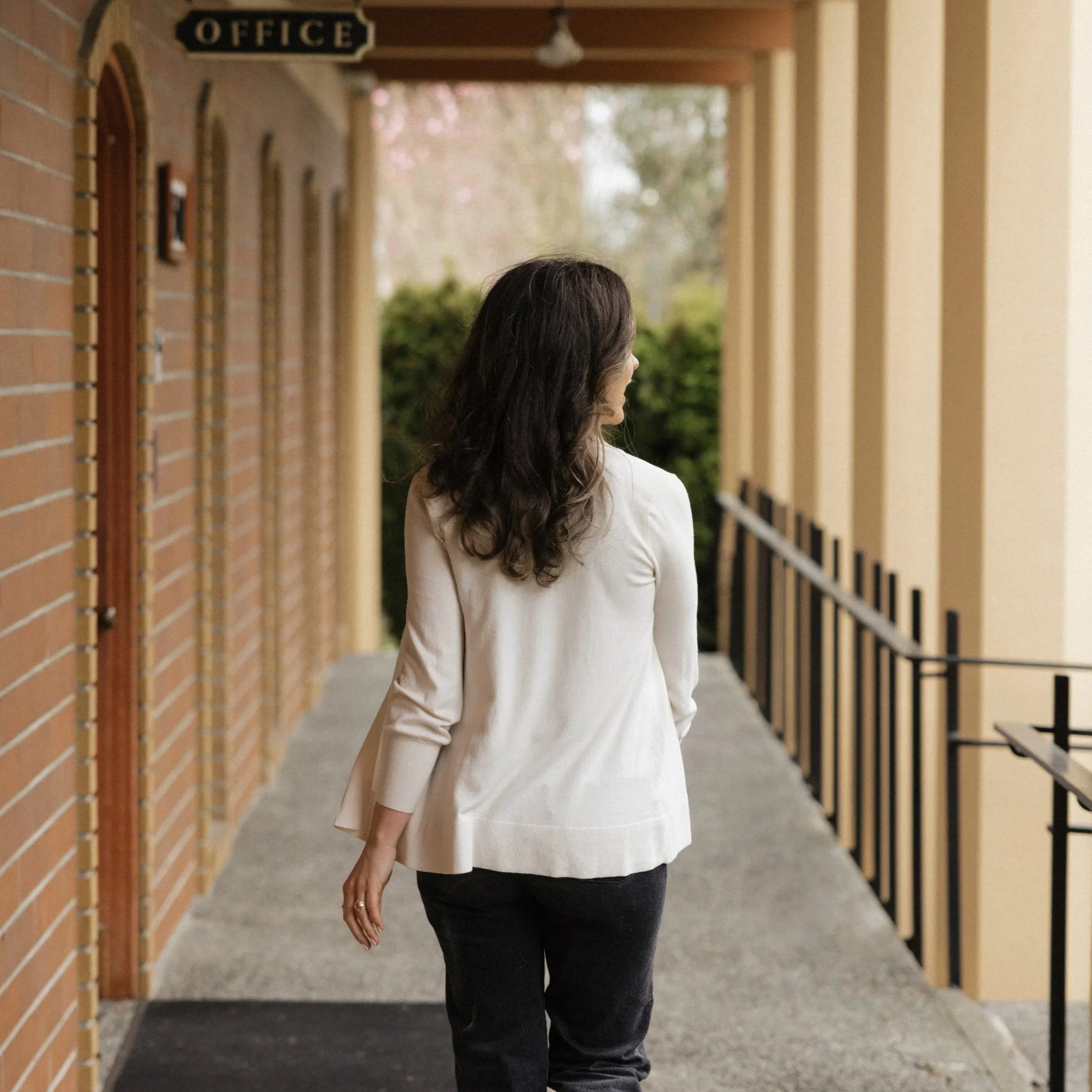 Dark haired woman walking through an outdoor covered walkway
