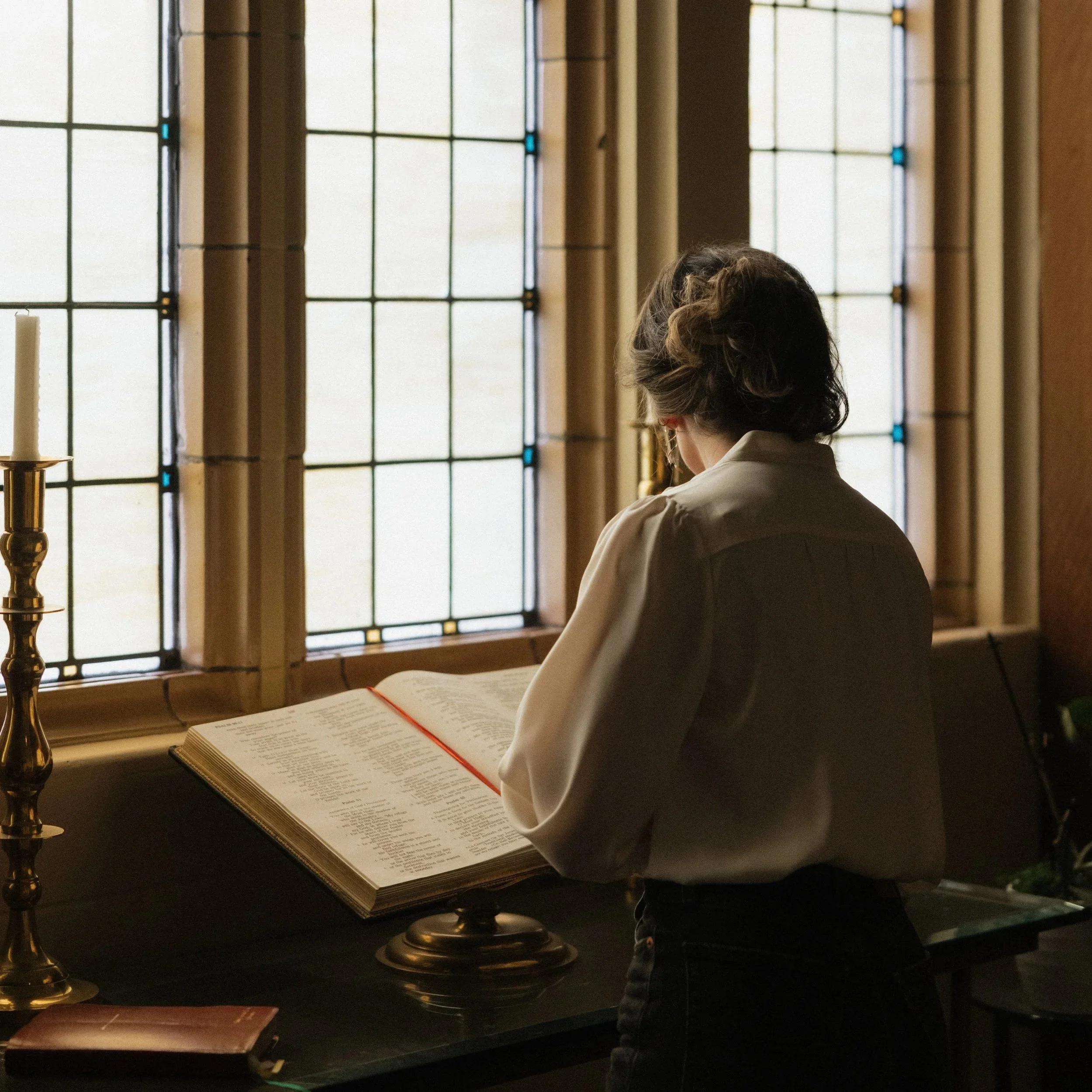 Woman standing in front of stained glass windows and a large book