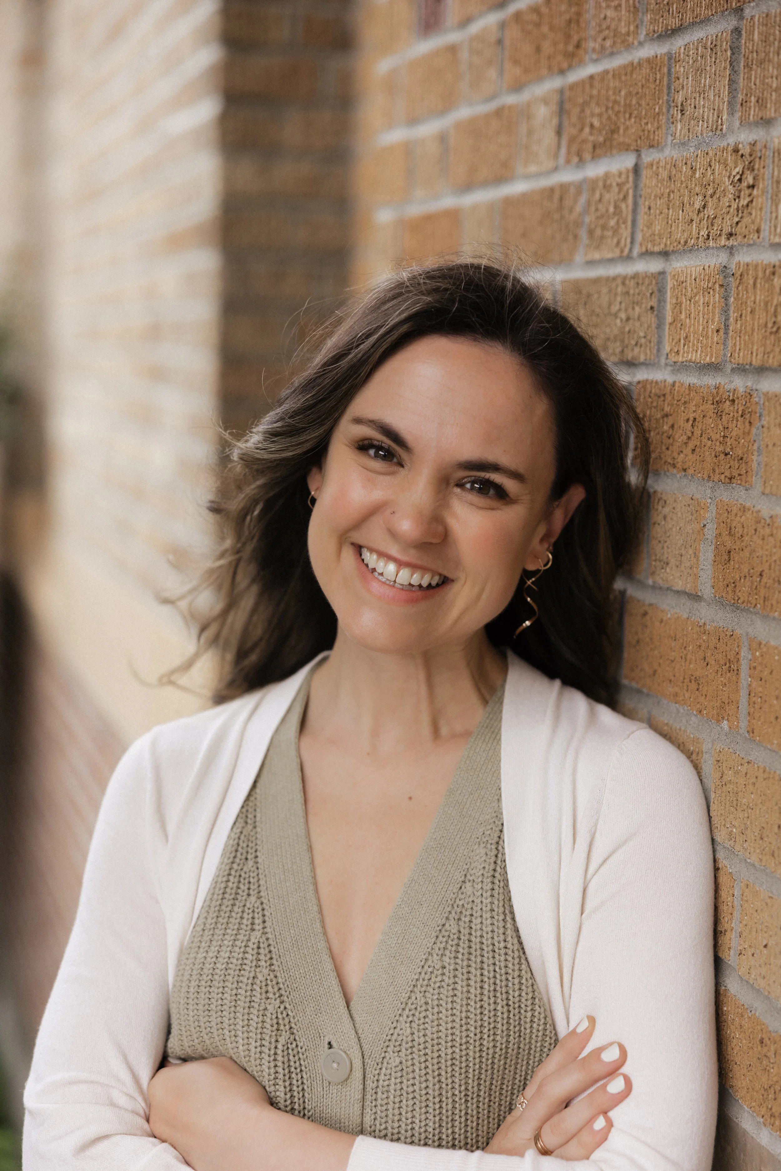 Lynnette Oss Connell, a burnout coach, workshop leader, and keynote speaker, smiles while leaning against a brick wall.