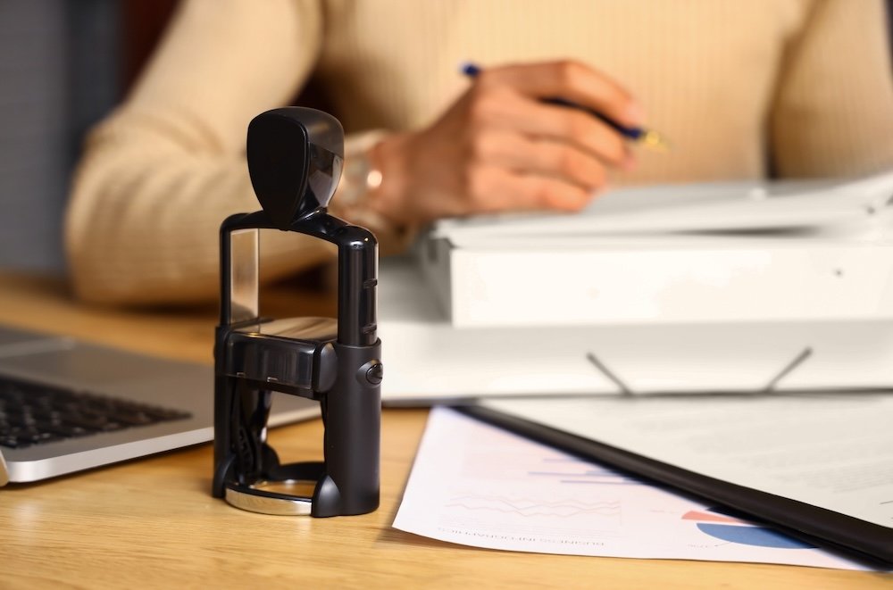 A tax and notary professional at Russell Partners LLC in Newton, MA sits at her desk with the notary stamp in focus.