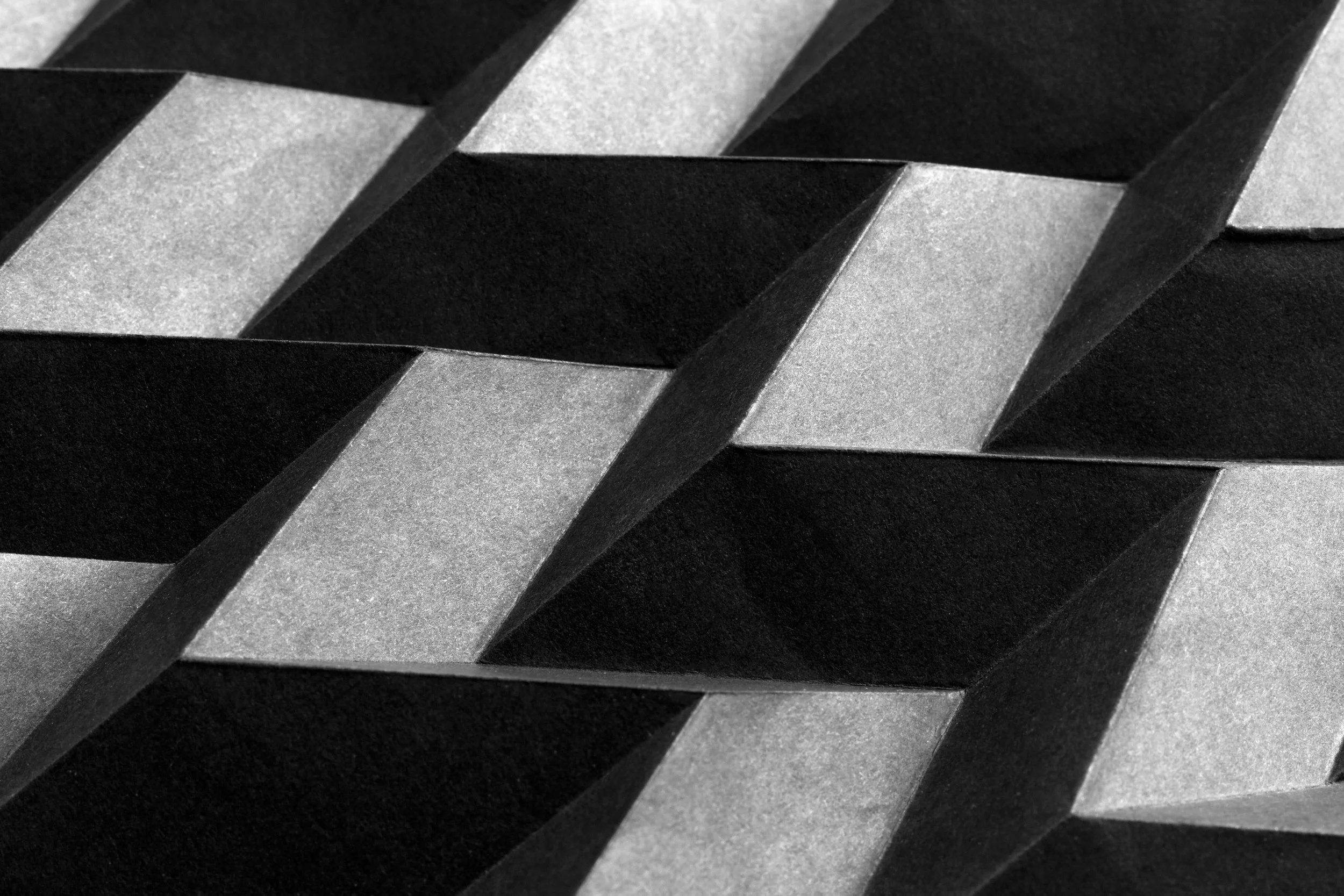 Close-up of a woven pattern made from black and gray cardboard strips.
