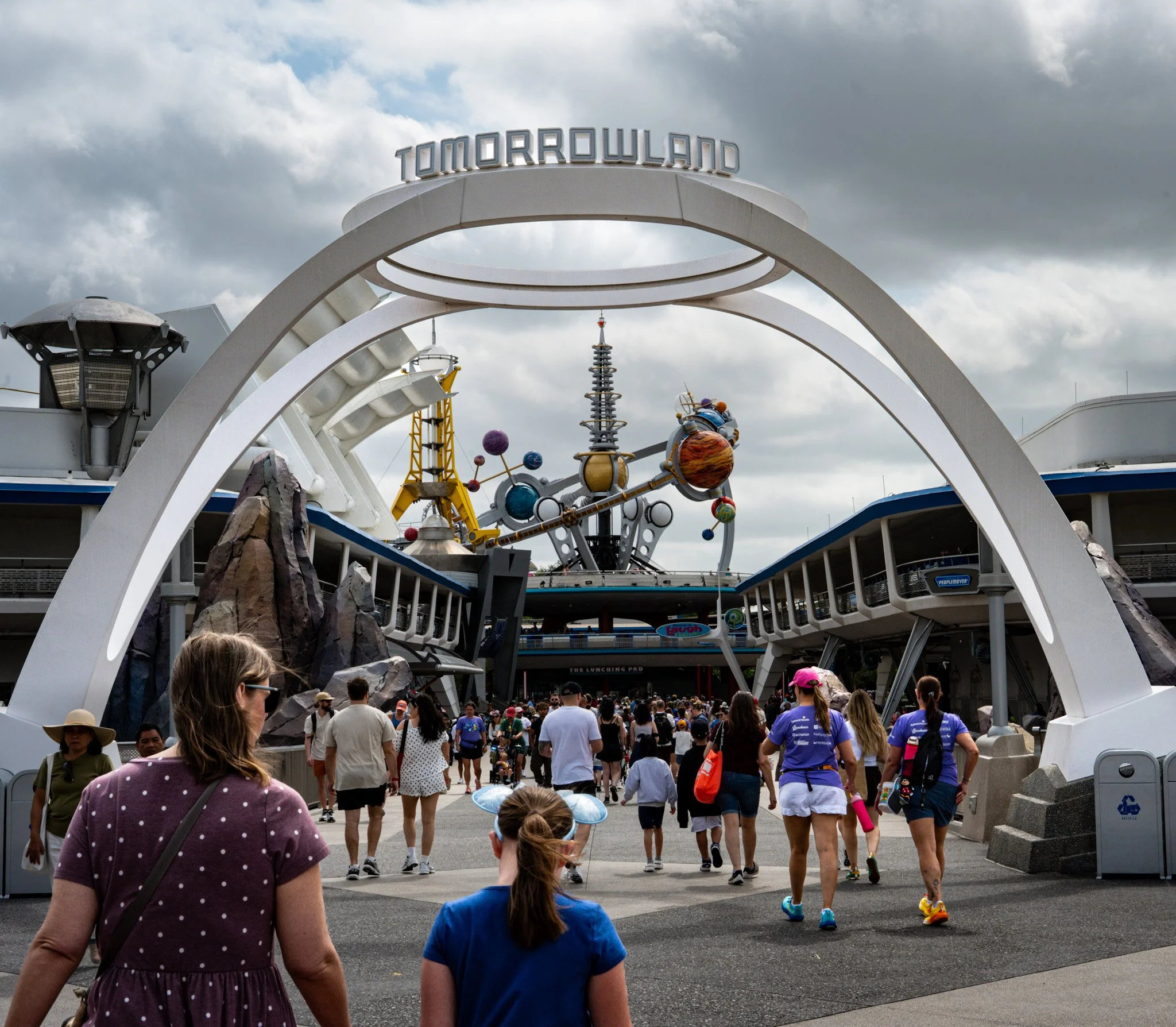 People walking towards  'Tomorrowland' at Disney world.