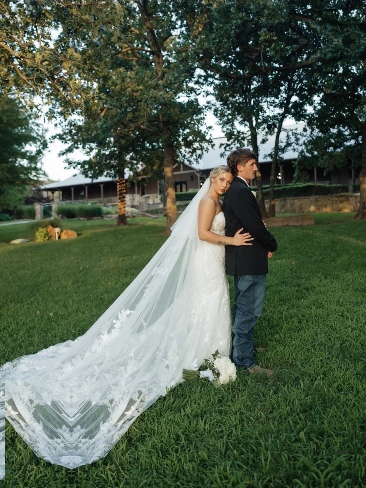Bride and groom portrait with a long cathedral veil on the lawn at The Springs
