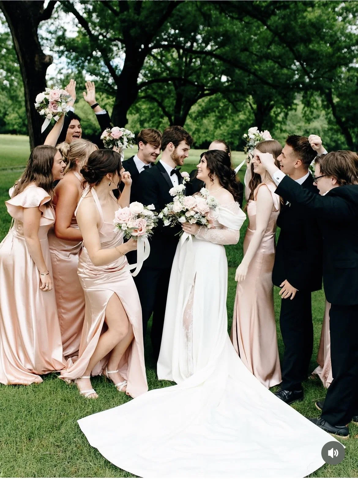 Bride and groom celebrating with bridesmaids and groomsmen outdoors in a leafy park