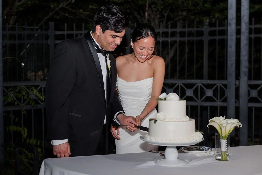Bride and groom cutting their two-tier white cake with white roses at their Philbrook reception