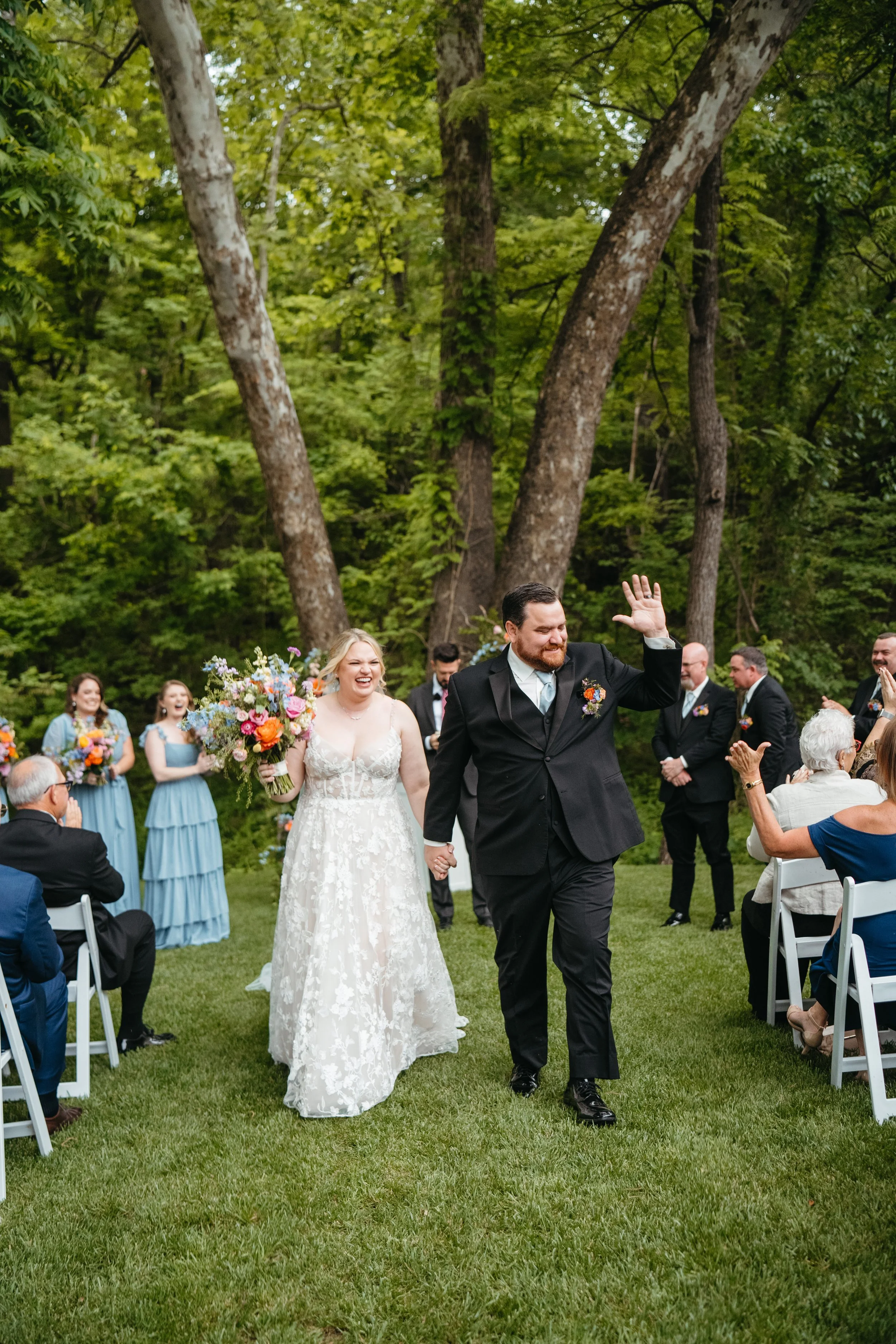 Bride and groom laughing down the aisle in front of colorful wedding backdrop