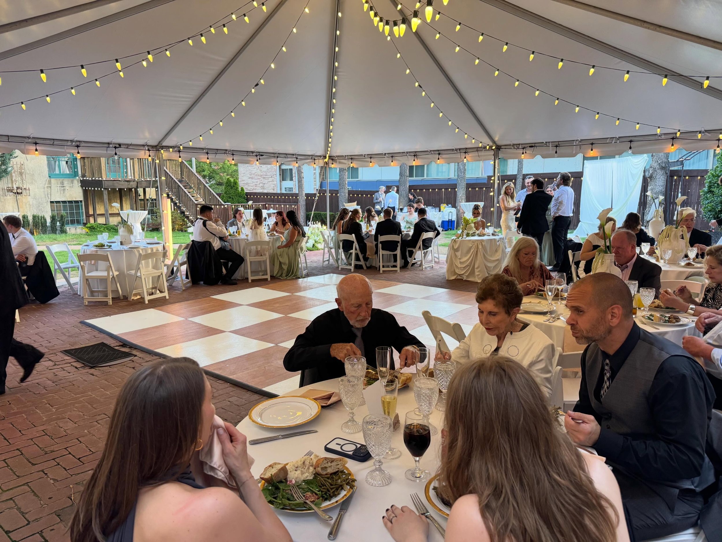 Brown and white dance floor under the tent with twinkle lights