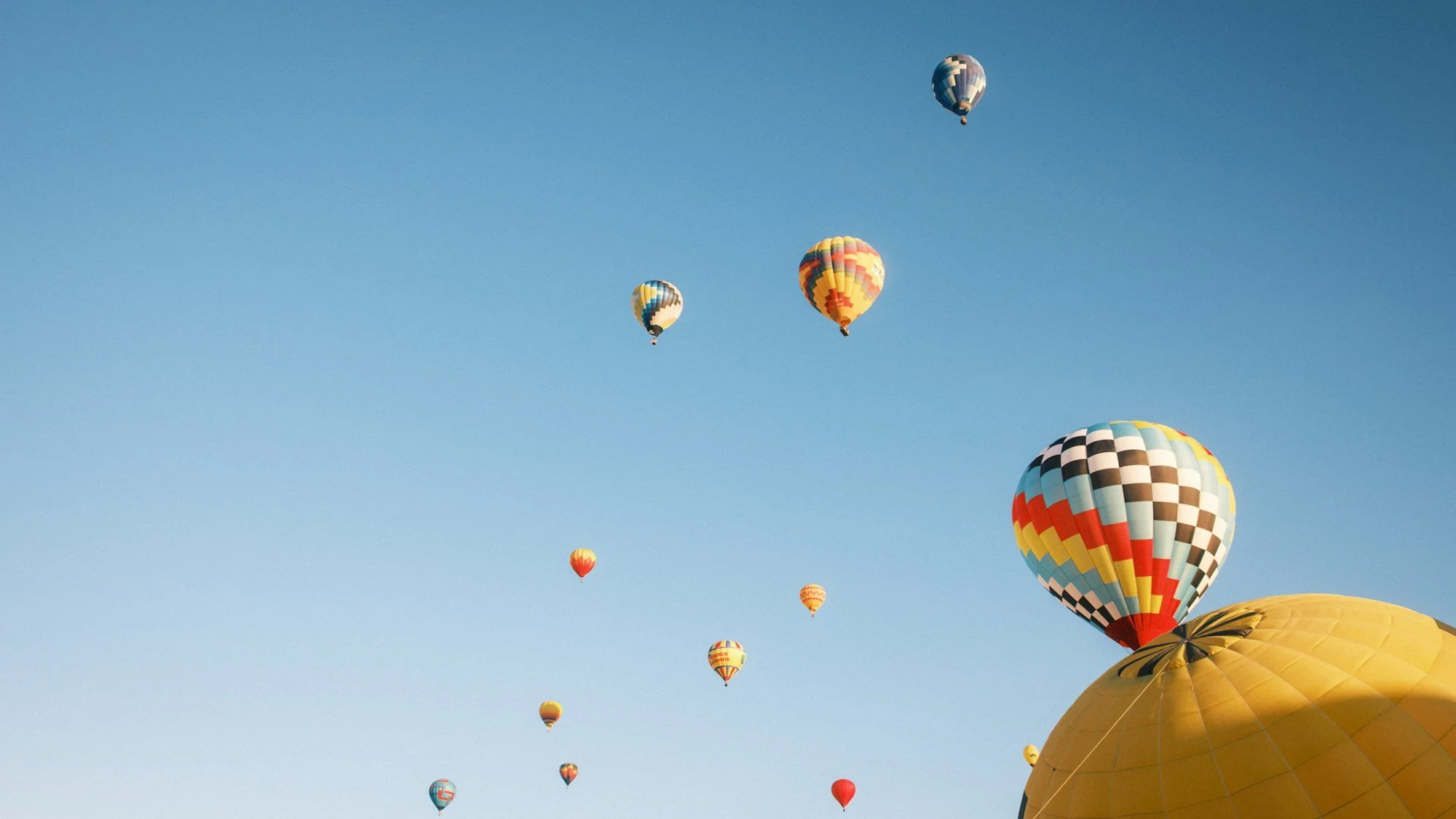 Hot air balloons drifting across a clear blue sky