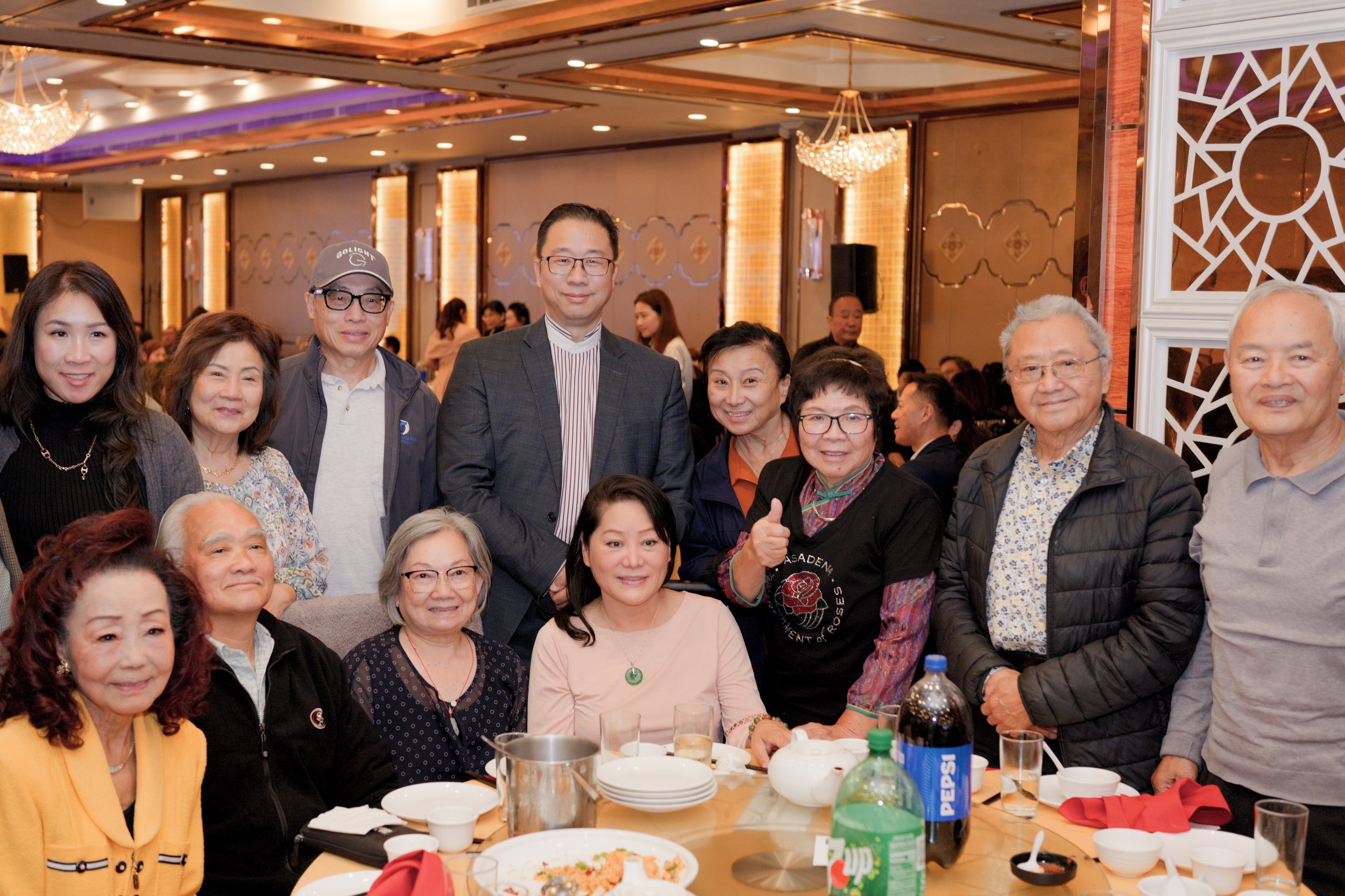 A group of people gathered at a banquet table in a decorated, elegant venue, smiling for the photo.
