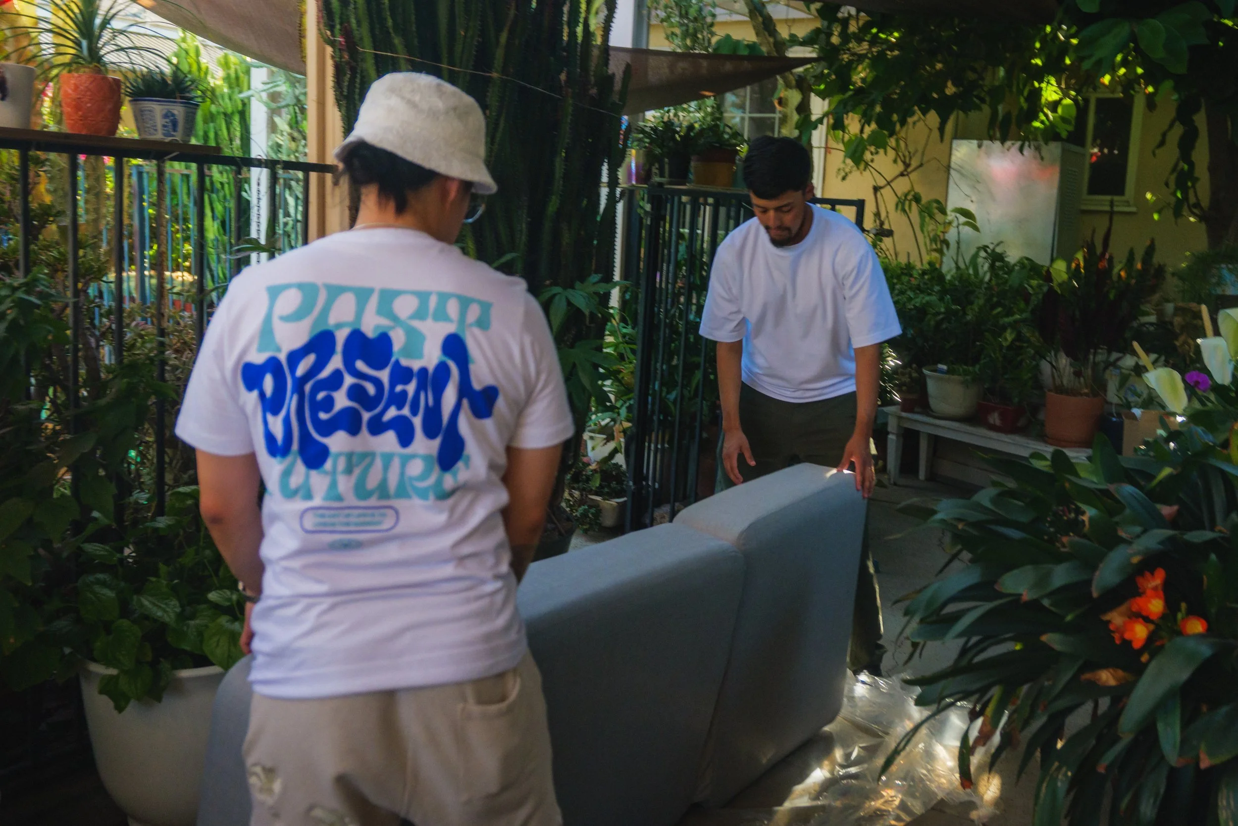Behind the scenes: Thomas and Gilbert setting up the gray Solaris chaise lounge on a plant-filled patio