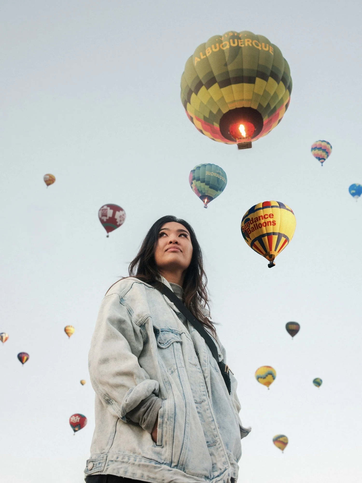 A friend posing on the field with balloons floating overhead