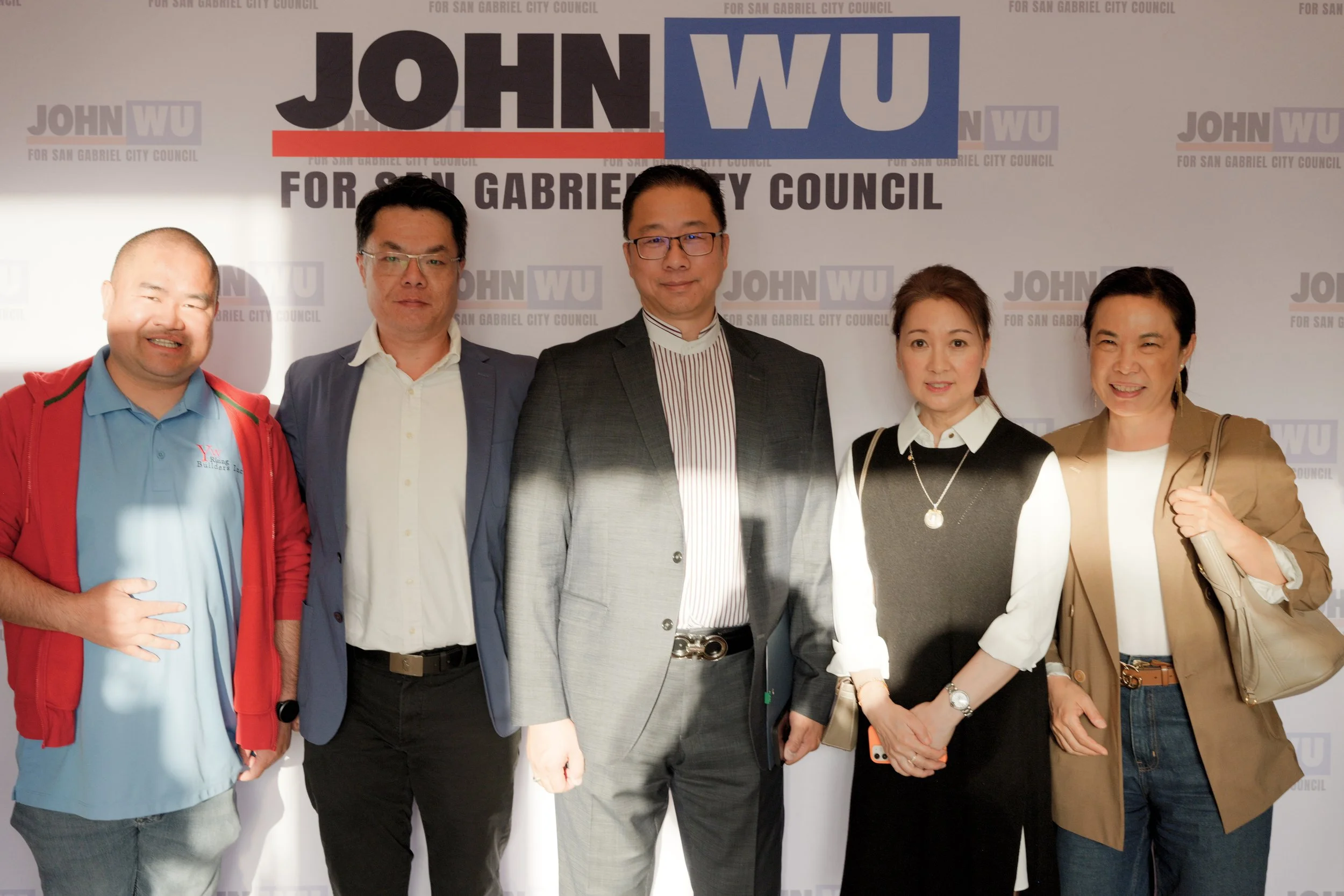 Group of six people standing in front of a backdrop with 'John Wu for San Gabriel City Council' logo, smiling and posing for the photo.