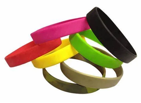 Stacked colorful silicone wristbands in various colors including pink, red, yellow, green, black, and beige.